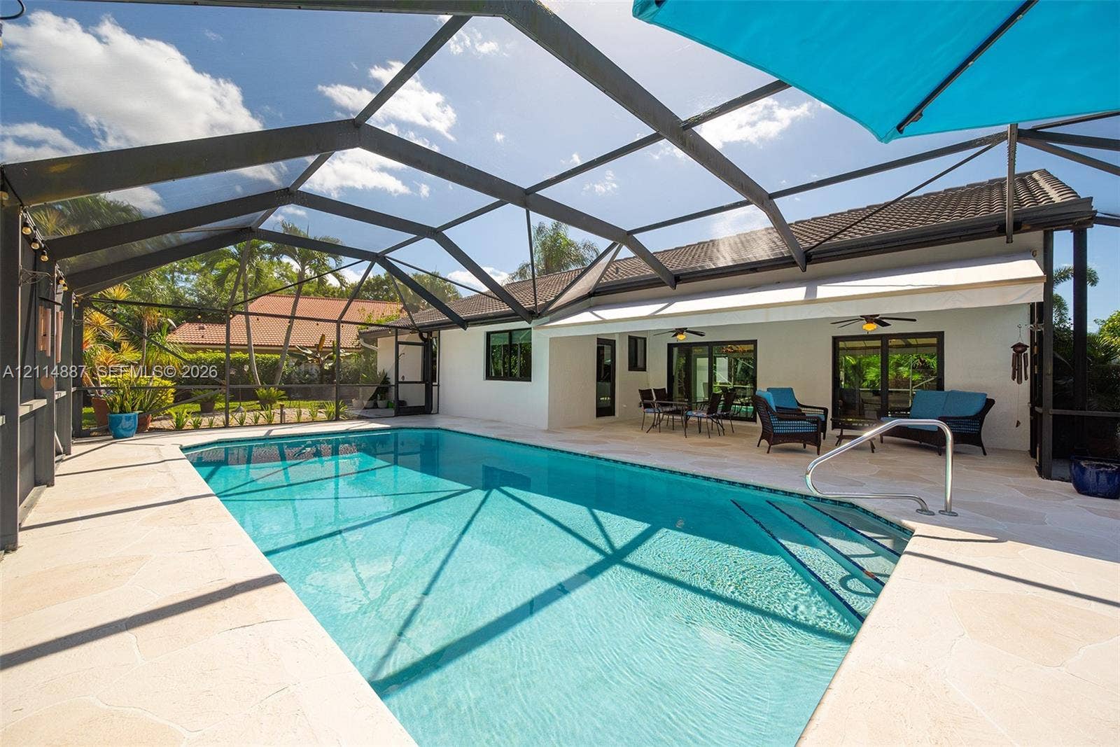 5722 Aspen Ridge Circle, Delray Beach, FL 33484 Screened lanai featuring a swimming pool, stone-paver decking, and a retractable awning
