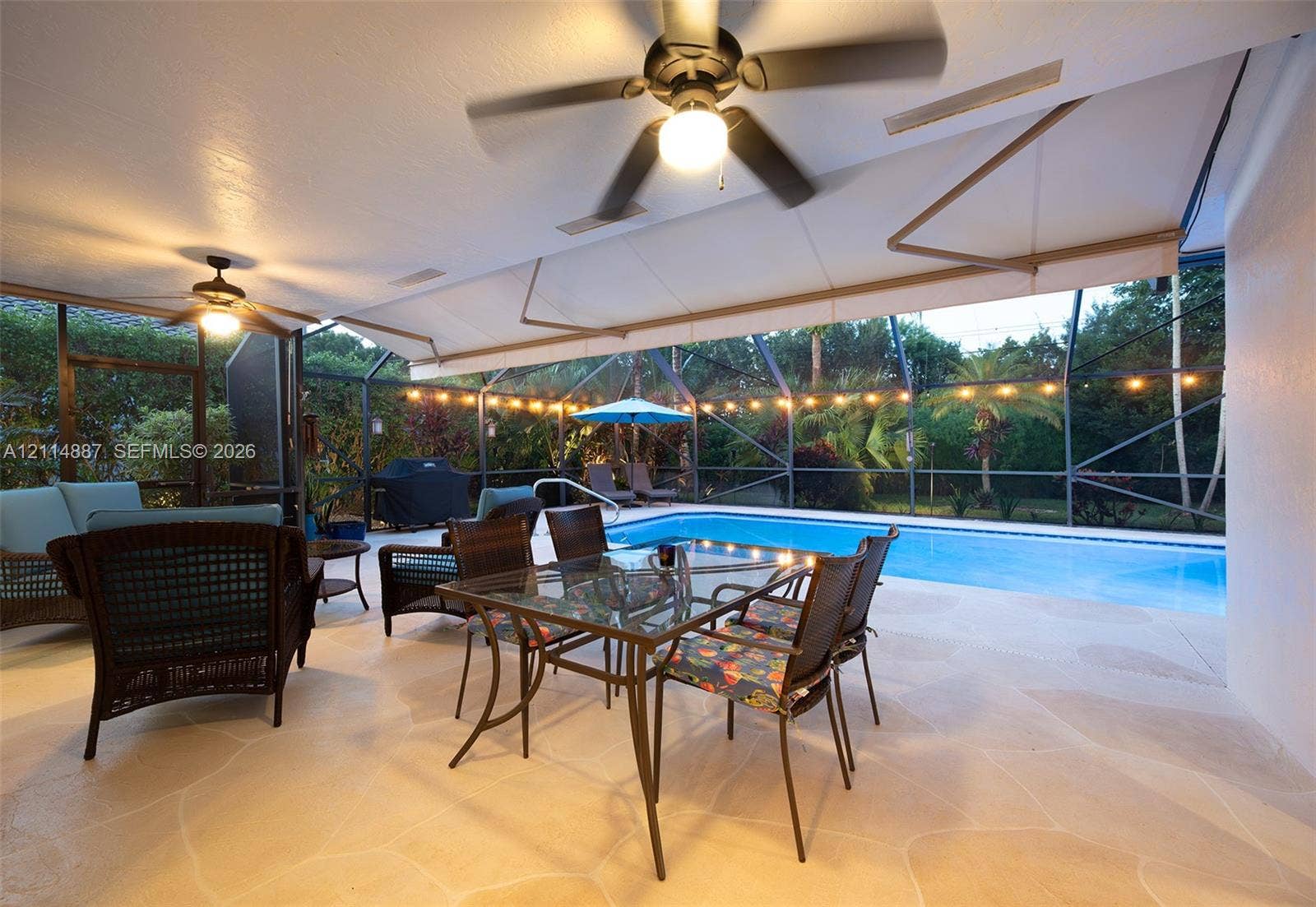 5722 Aspen Ridge Circle, Delray Beach, FL 33484 Covered lanai featuring paver flooring, dual ceiling fans, retractable awning, and screen enclosure over a swimming pool
