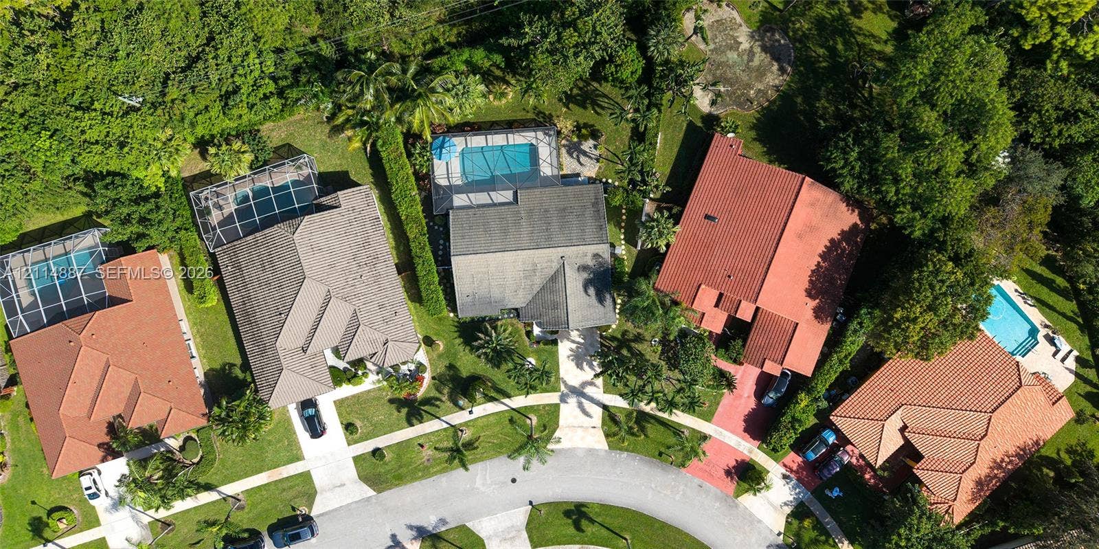 5722 Aspen Ridge Circle, Delray Beach, FL 33484 Aerial perspective of residential properties featuring concrete tile roofing, paved driveways, and screened-in swimming pools surrounded by mature trees