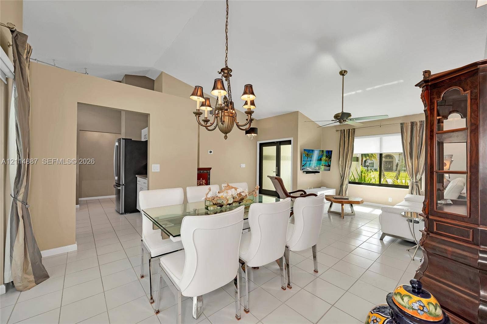5722 Aspen Ridge Circle, Delray Beach, FL 33484 Open-concept area featuring vaulted ceilings, neutral wall tones, ceramic tile flooring, a multi-arm chandelier, and a ceiling fan