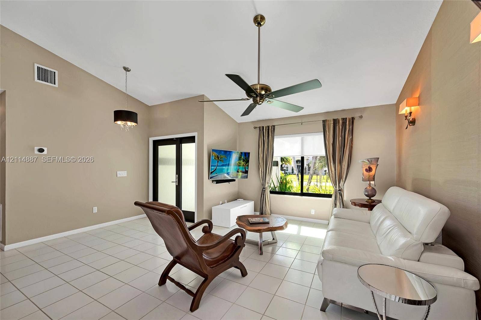 5722 Aspen Ridge Circle, Delray Beach, FL 33484 Vaulted ceiling with an integrated multi-blade ceiling fan, neutral wall finishes, tile flooring, and custom wall-mounted lighting fixtures