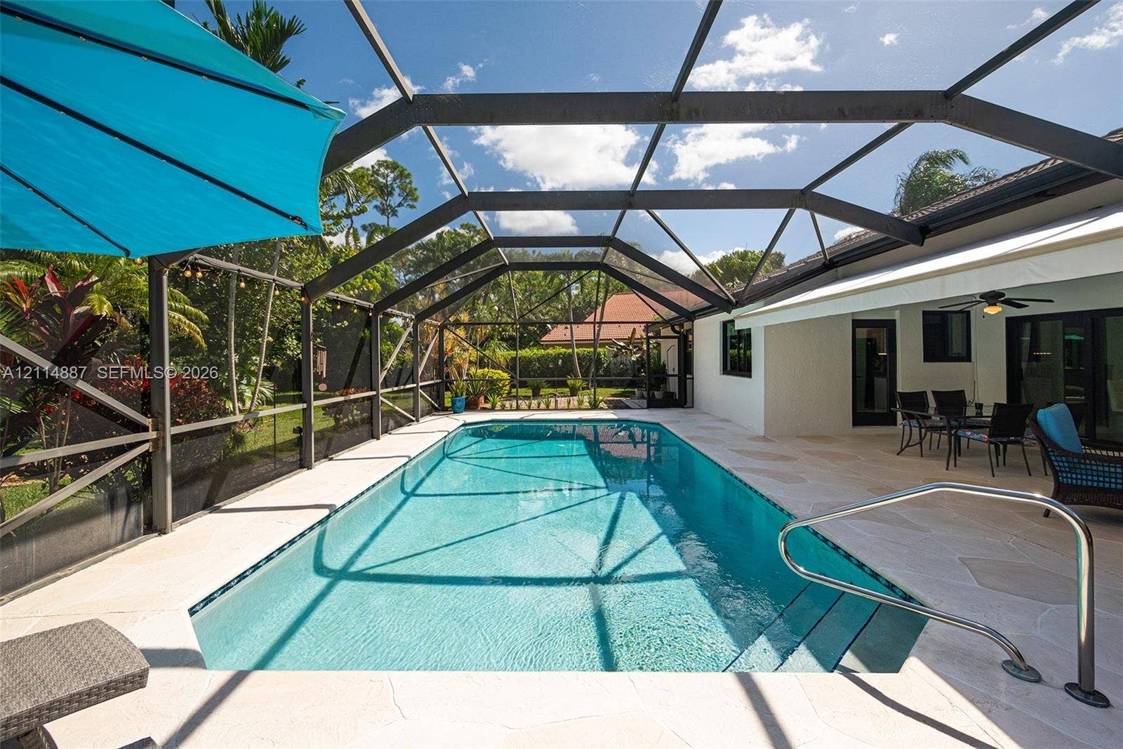 5722 Aspen Ridge Circle, Delray Beach, FL 33484 Screen-enclosed rectangular swimming pool with built-in stairs, metal handrail, and light-toned paver pool deck