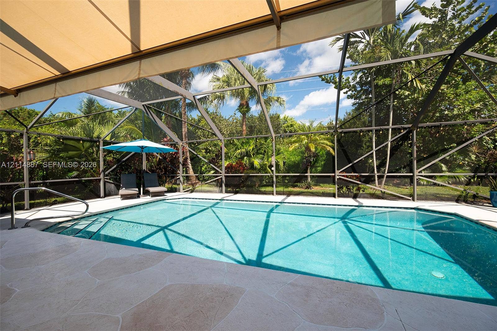 5722 Aspen Ridge Circle, Delray Beach, FL 33484 Screened-in pool area featuring a stone-paver deck, built-in metal handrails, and a retractable fabric awning
