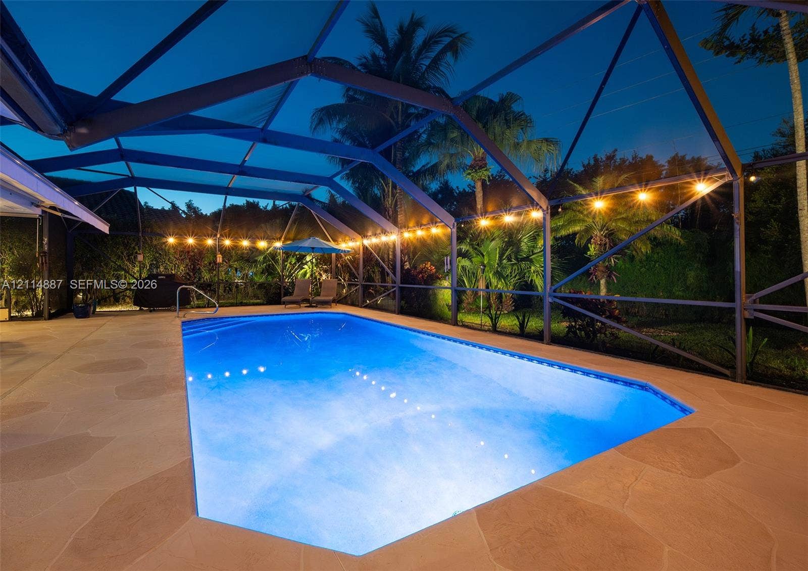 5722 Aspen Ridge Circle, Delray Beach, FL 33484 Screen-enclosed swimming pool featuring a natural stone-style deck, integrated pool lighting, and built-in metal handrail