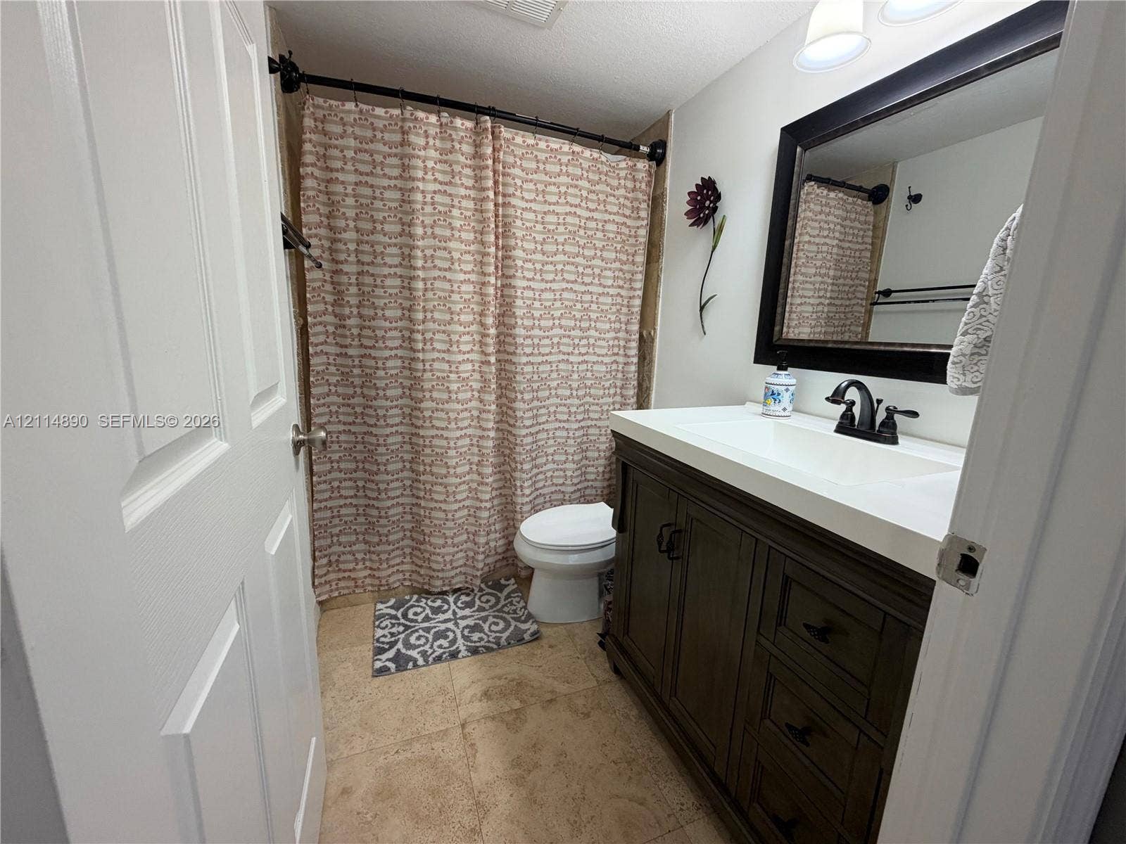 610 S Park Road, #28-1, Hollywood, FL 33021 Bathroom featuring a vanity with dark wood-finish cabinetry, a white countertop with an integrated sink, a dark-framed mirror, and a curved shower rod