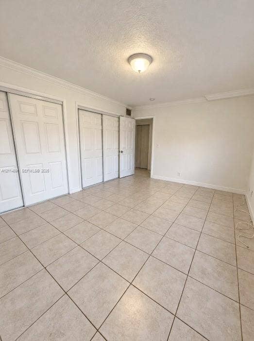 Neutral-toned ceramic tile flooring, multi-panel sliding closet doors, and crown molding detail
