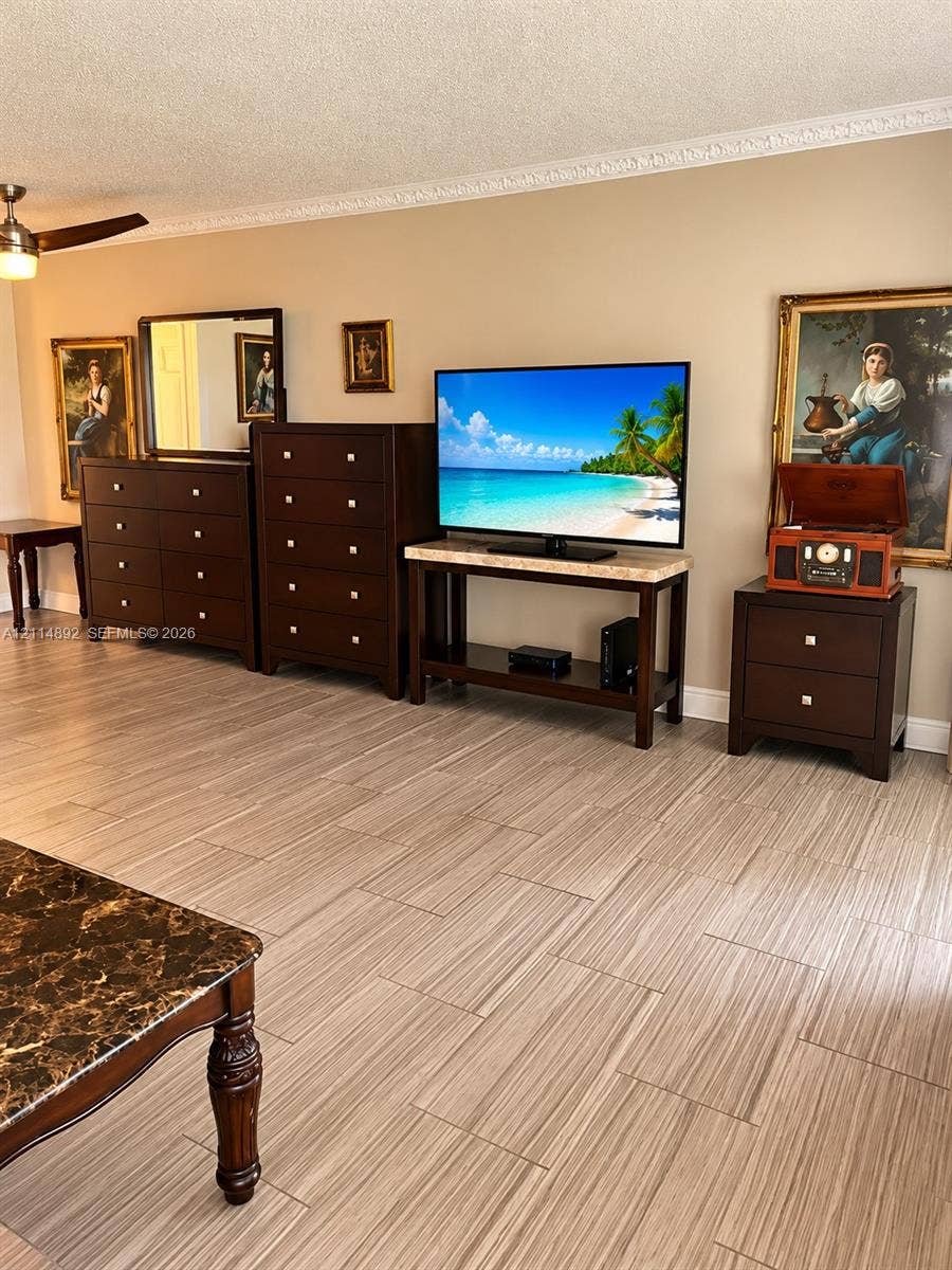 582 Durham U, #582, Deerfield Beach, FL 33442 Neutral interior featuring wood-finish tile flooring, decorative crown molding, and a ceiling fan with integrated lighting