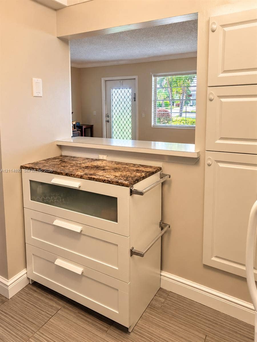 582 Durham U, #582, Deerfield Beach, FL 33442 Custom cabinetry featuring a glass-panel drawer, stone-finish countertop, side-mounted metallic hardware, and integrated full-height storage cabinetry