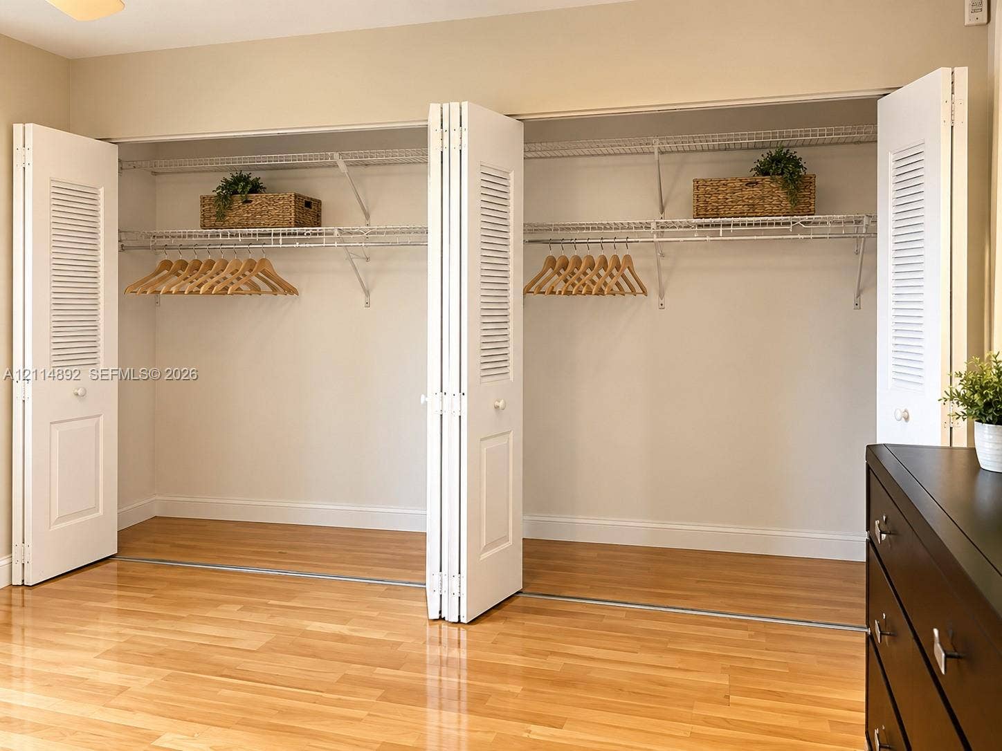 582 Durham U, #582, Deerfield Beach, FL 33442 Reach-in closet featuring white louvered bi-fold doors, wire shelving, and wood-finish flooring