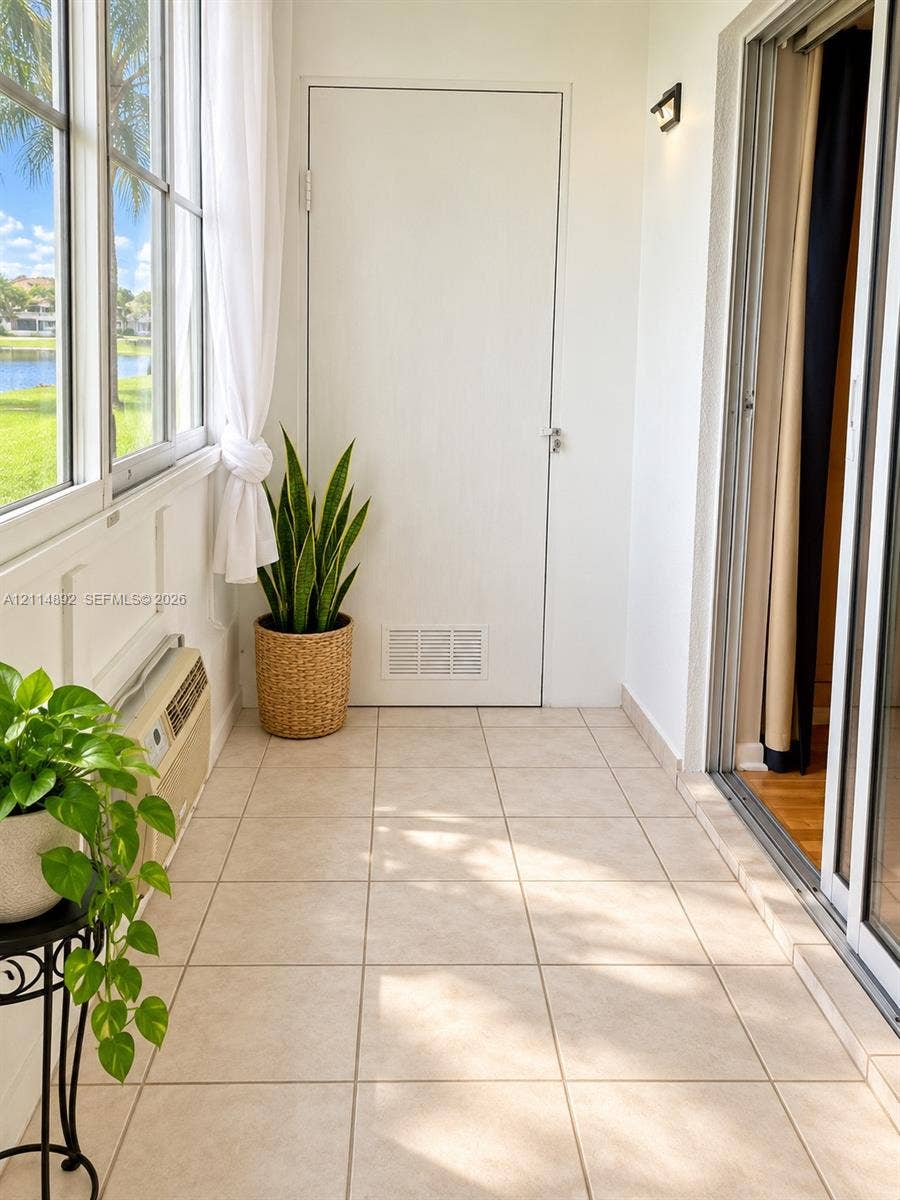 582 Durham U, #582, Deerfield Beach, FL 33442 Enclosed patio featuring large-format tile flooring, expansive windows, wall-mounted lighting, and a neutral white color palette
