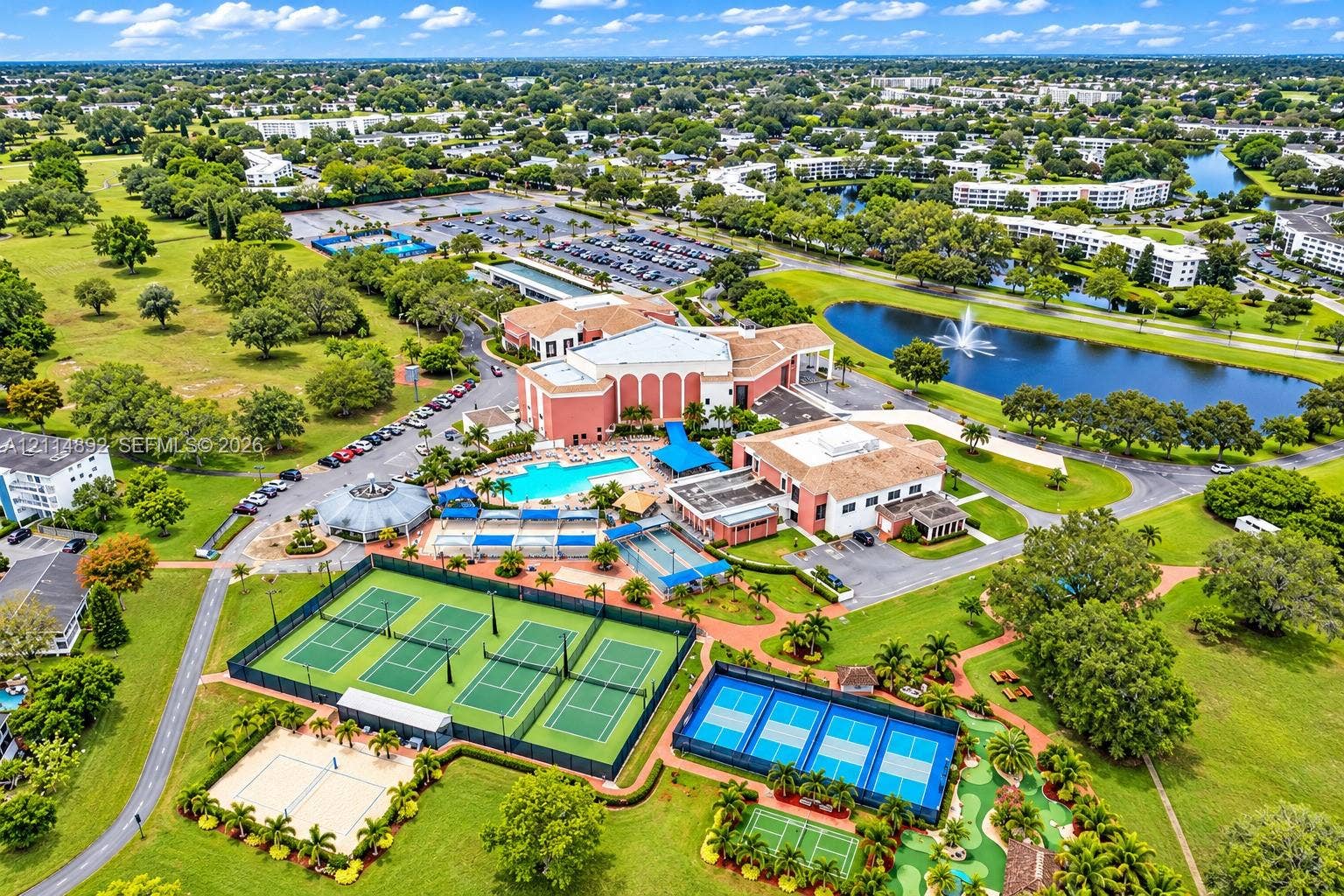 582 Durham U, #582, Deerfield Beach, FL 33442 Aerial perspective of a multi-facility recreational complex featuring a swimming pool, multiple tennis courts, pickleball courts, and a putting green