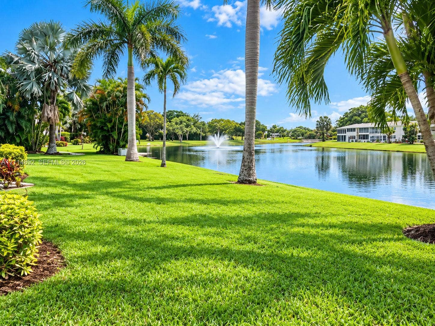 582 Durham U, #582, Deerfield Beach, FL 33442 Expansive grounds featuring a manicured lawn, mature palm trees, a large pond, and a built-in water fountain
