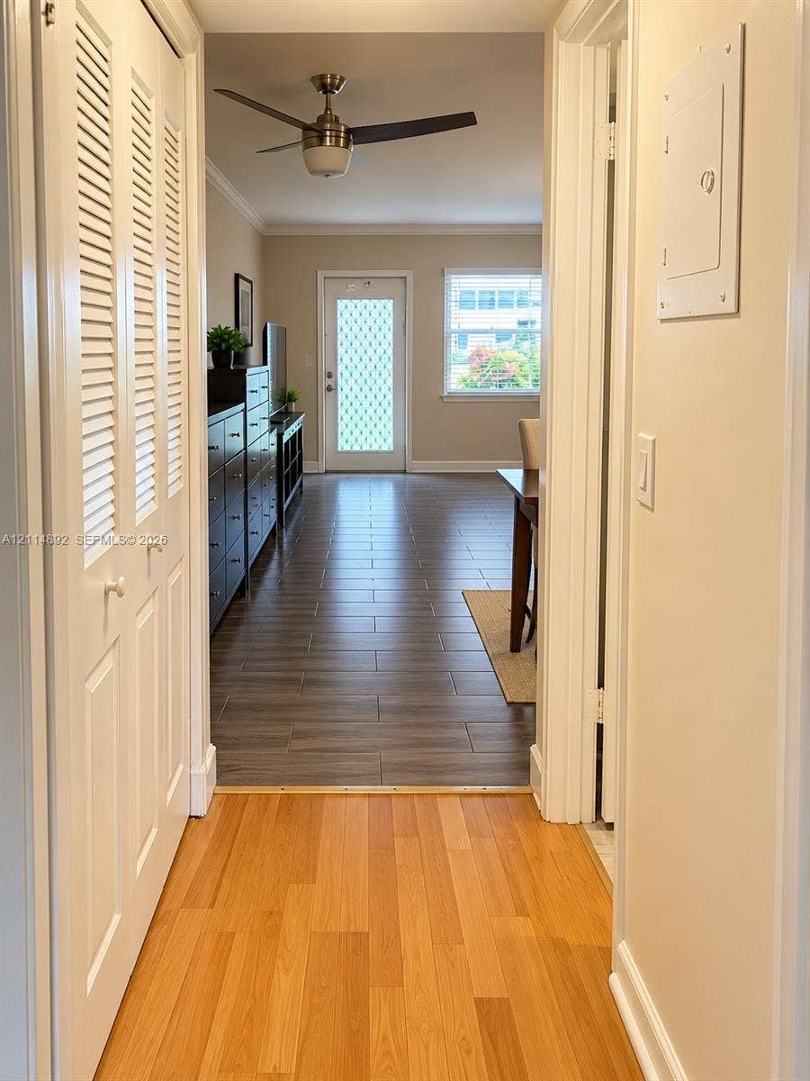 582 Durham U, #582, Deerfield Beach, FL 33442 Interior hallway featuring light-toned wood-finish flooring, white louvered closet doors, and a ceiling-mounted fan in the common area with dark wood-finish tile flooring