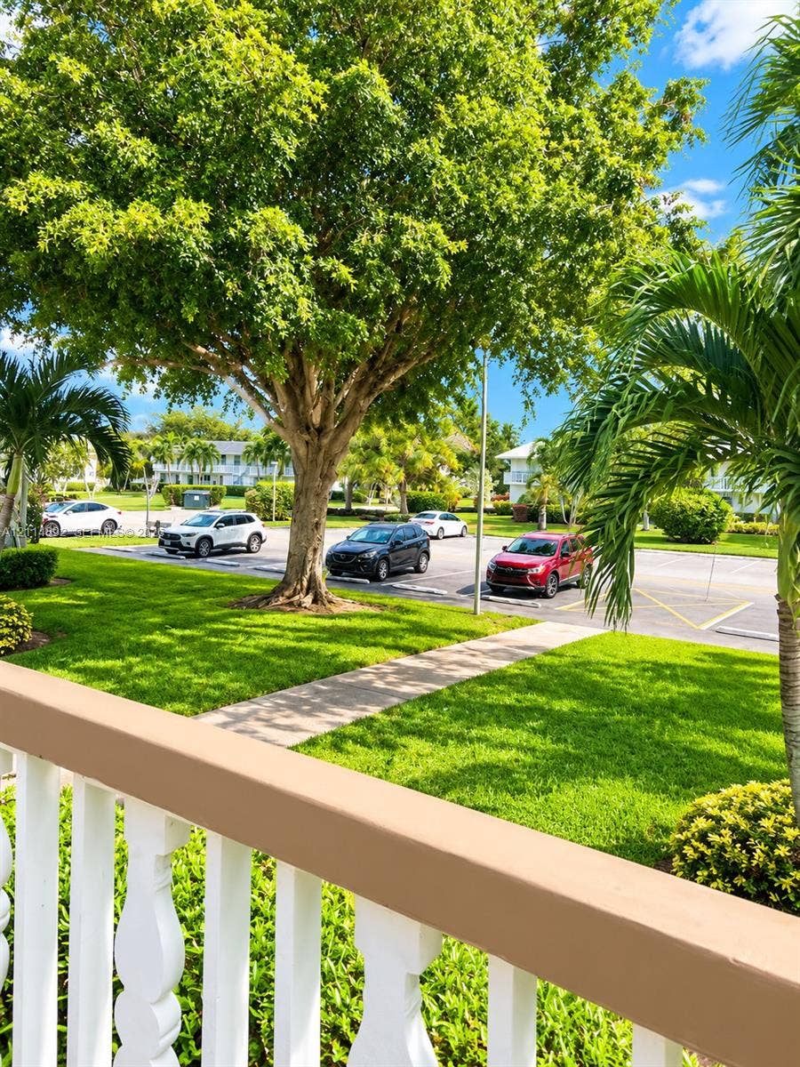 582 Durham U, #582, Deerfield Beach, FL 33442 Outdoor space featuring a painted wood railing, paved pedestrian walkway, mature landscaping, and green lawn