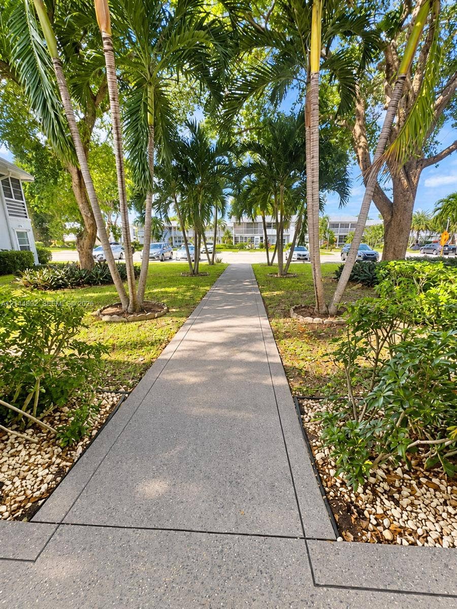 582 Durham U, #582, Deerfield Beach, FL 33442 Concrete walkway lined with mature palm trees, manicured landscaping, and stone-accented garden beds
