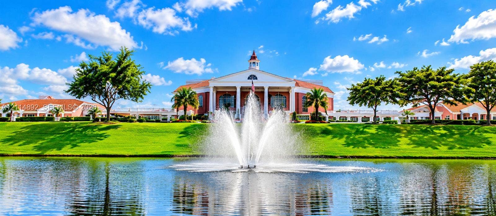 582 Durham U, #582, Deerfield Beach, FL 33442 Colonial-inspired architecture featuring a central cupola and multi-columned portico, situated on a manicured waterfront lot with a central water feature and mature landscaping