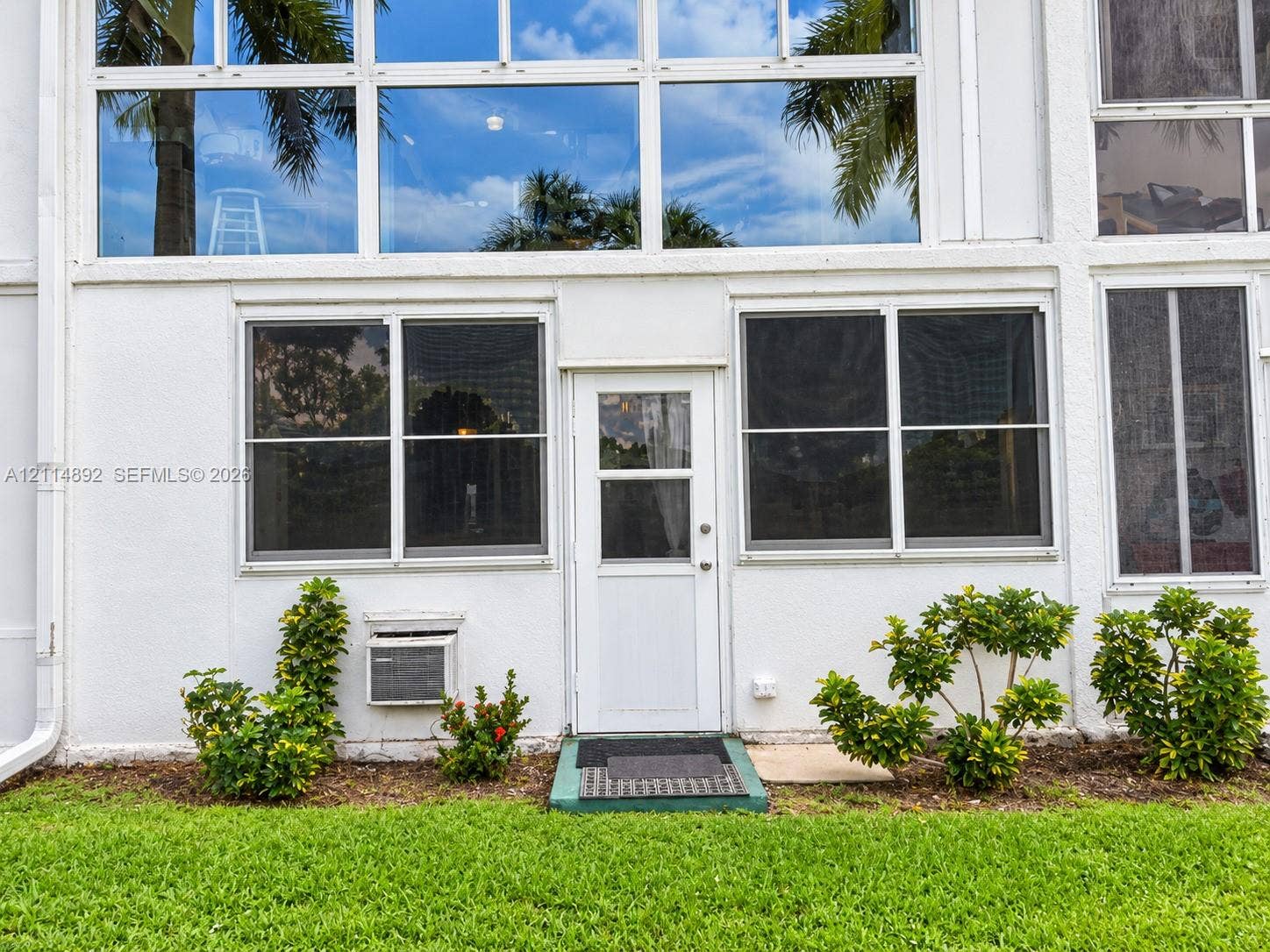 582 Durham U, #582, Deerfield Beach, FL 33442 Exterior facade featuring multi-story window arrays, a central glass-panel entry door, and manicured foundation landscaping