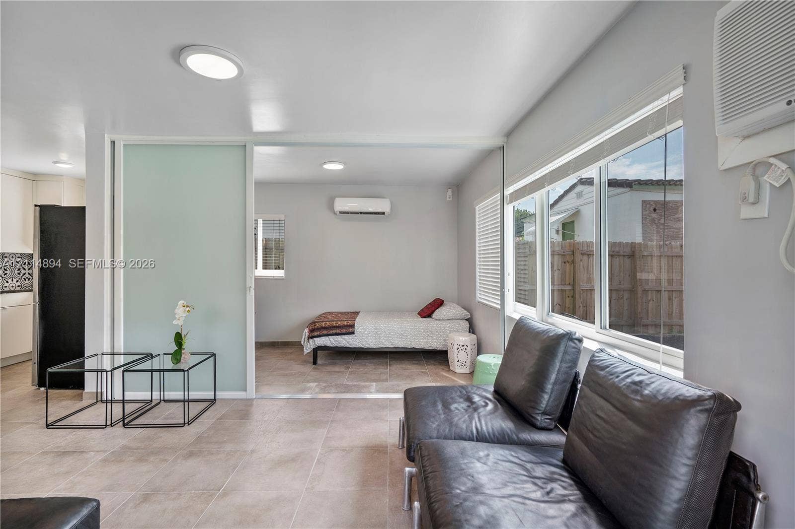 Large-format ceramic tile flooring, frosted glass sliding partition, wall-mounted air conditioning units, and oversized picture windows
