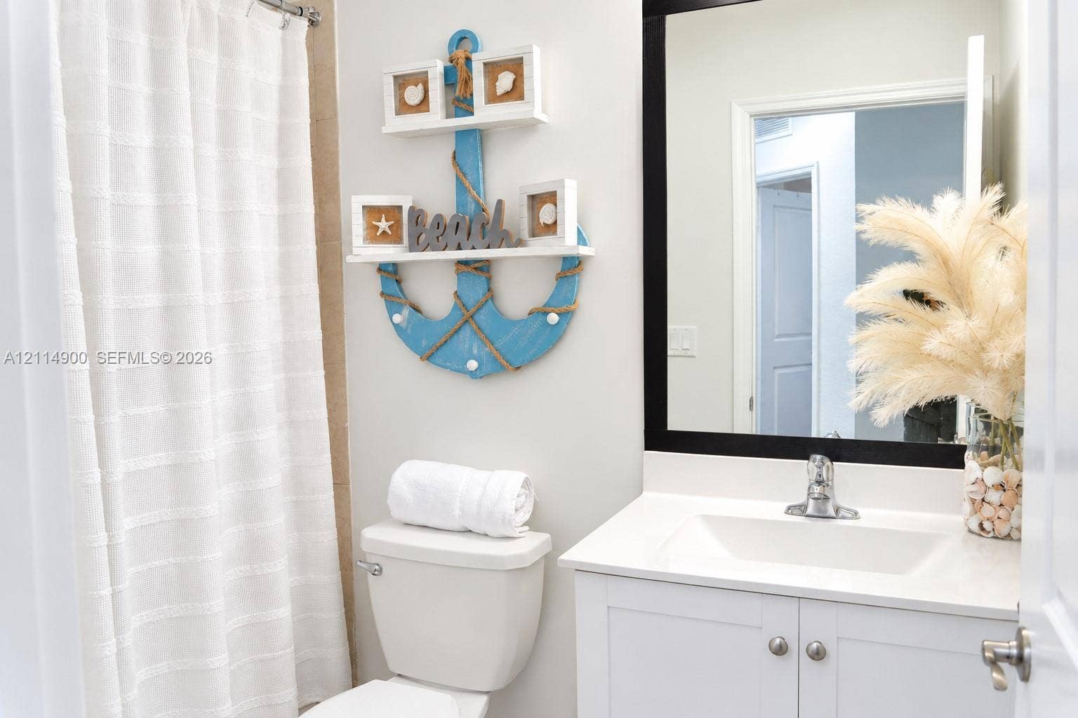 25048 SW 113th Place, Homestead, FL 33032 Bathroom vanity featuring a white cabinet base, stone countertop, integrated sink, and a rectangular mirror with a black frame