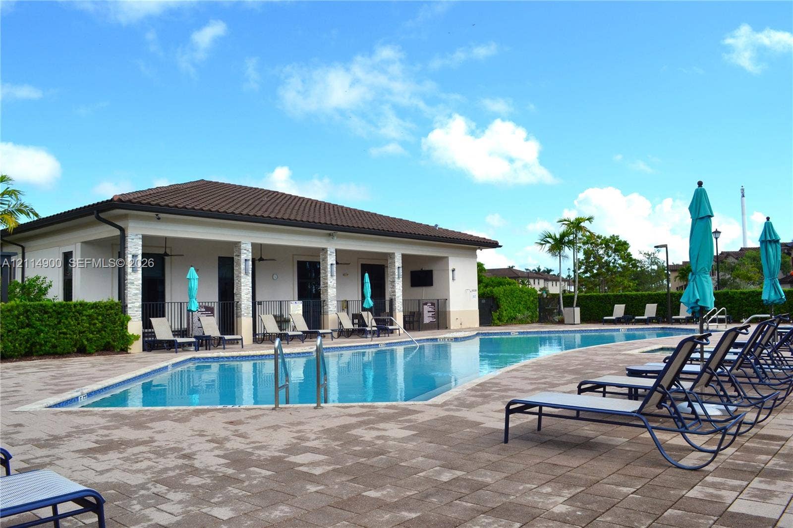 25048 SW 113th Place, Homestead, FL 33032 Outdoor swimming pool featuring a paved patio area, covered pavilion with stone-accented columns, and professional landscaping