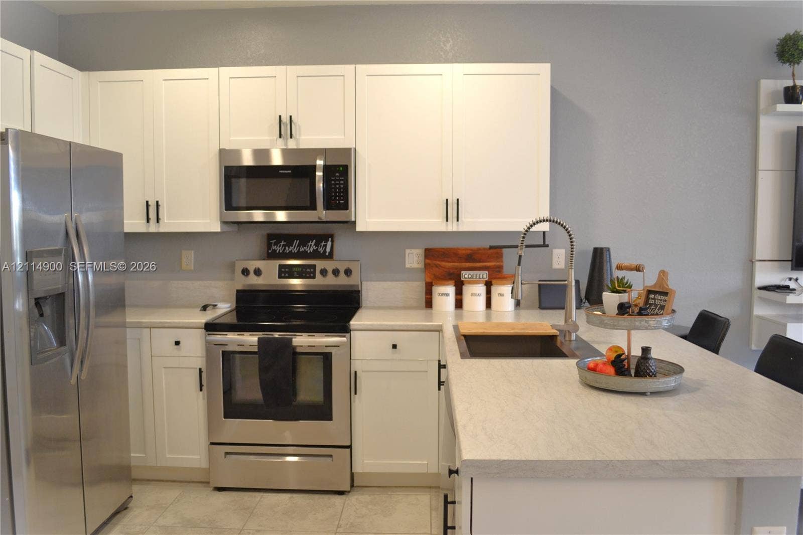 25048 SW 113th Place, Homestead, FL 33032 Kitchen featuring white shaker-style cabinetry, stainless steel appliances, neutral countertops, an undermount sink with a pull-down faucet, and a center island