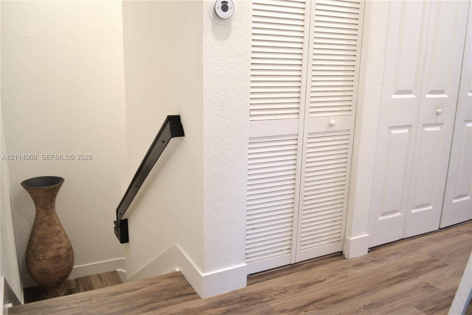 25048 SW 113th Place, Homestead, FL 33032 Wood-finish flooring, white louvered bifold closet doors, and a mounted black handrail