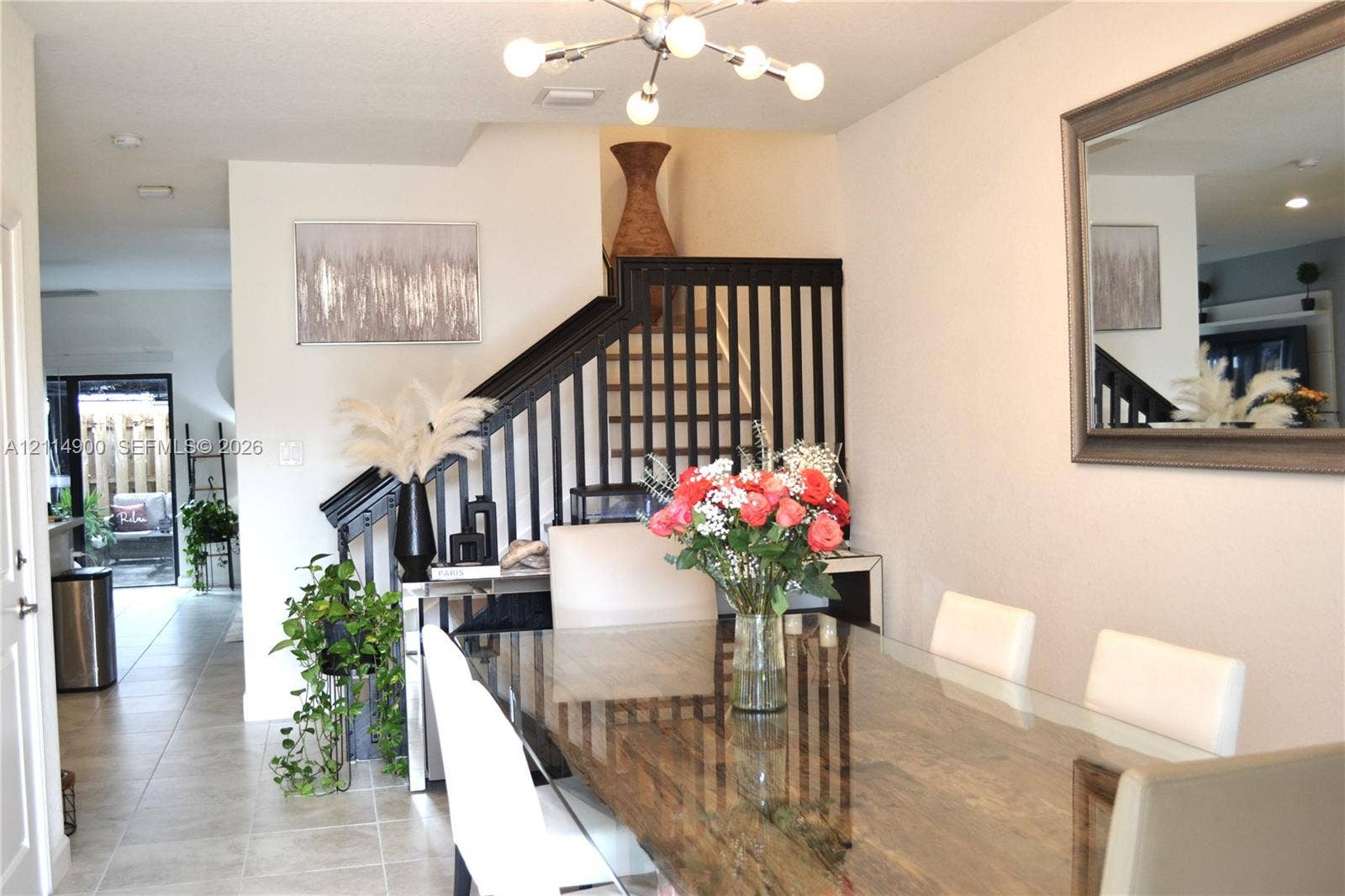 25048 SW 113th Place, Homestead, FL 33032 Neutral tile flooring, multi-arm sputnik-style chandelier, and black-painted wooden staircase balusters