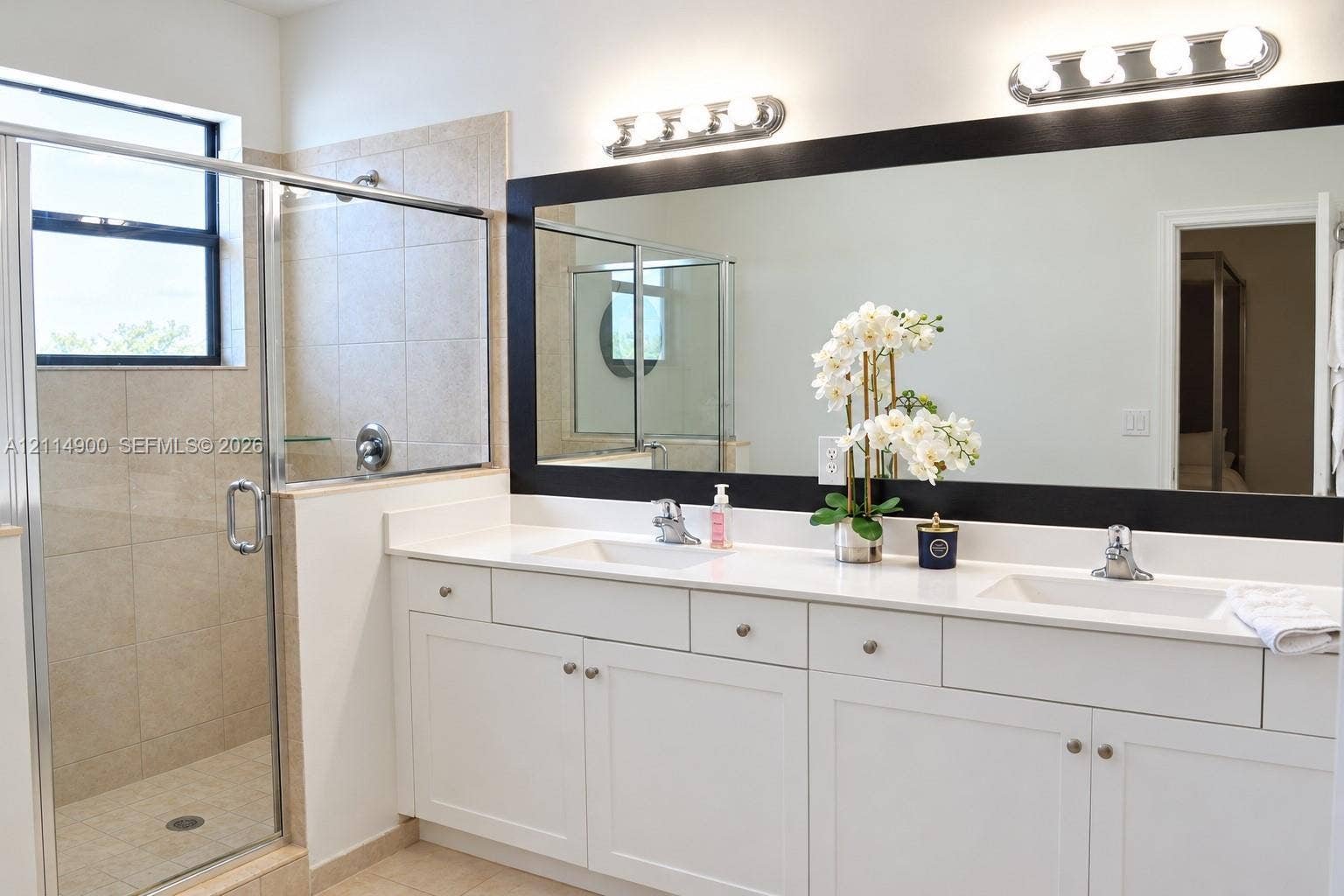 25048 SW 113th Place, Homestead, FL 33032 Double vanity featuring white cabinetry, quartz countertop, dual integrated sinks, and polished chrome fixtures, complemented by a walk-in shower with tiled surround and glass enclosure