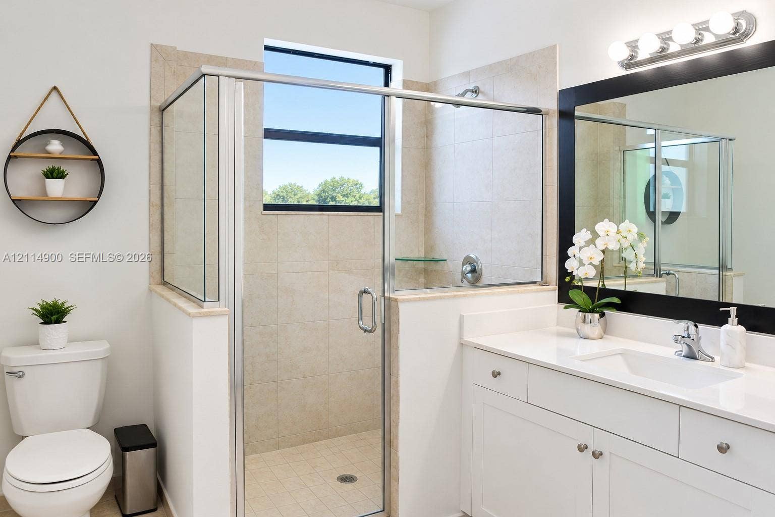 25048 SW 113th Place, Homestead, FL 33032 Bathroom featuring a glass-enclosed shower with tile surround, white cabinetry, solid-surface countertop, and a framed mirror with integrated lighting