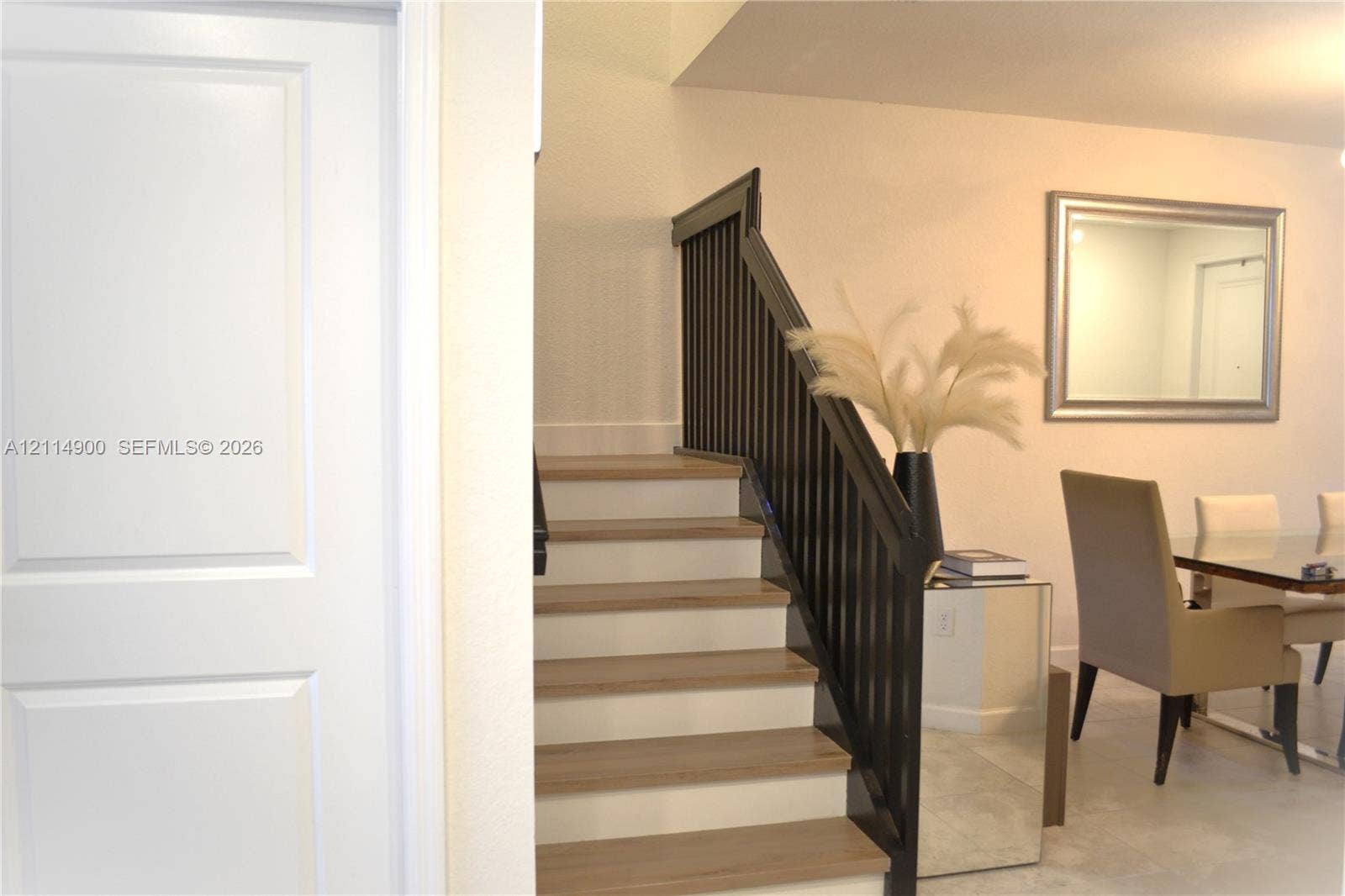 25048 SW 113th Place, Homestead, FL 33032 Staircase featuring light-tone wood treads, white risers, and a contrasting dark-finish handrail with vertical balusters
