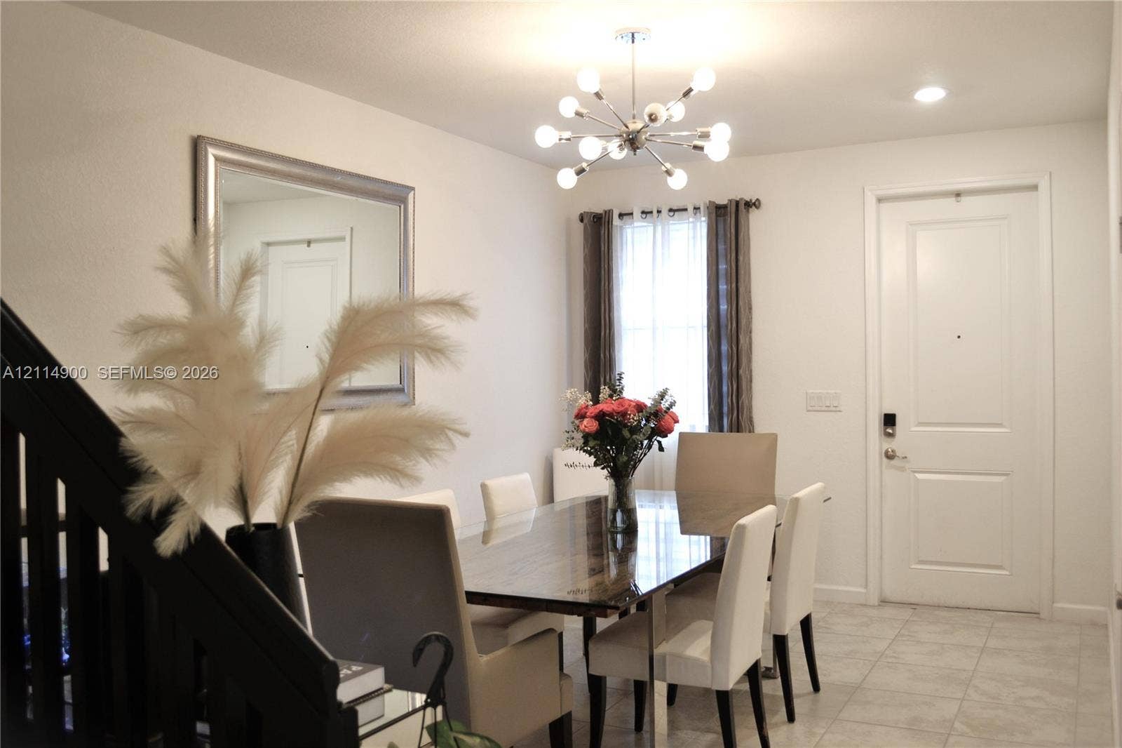 25048 SW 113th Place, Homestead, FL 33032 Open-concept interior featuring light-toned tile flooring, a multi-arm metallic sputnik-style chandelier, and a panelled entry door