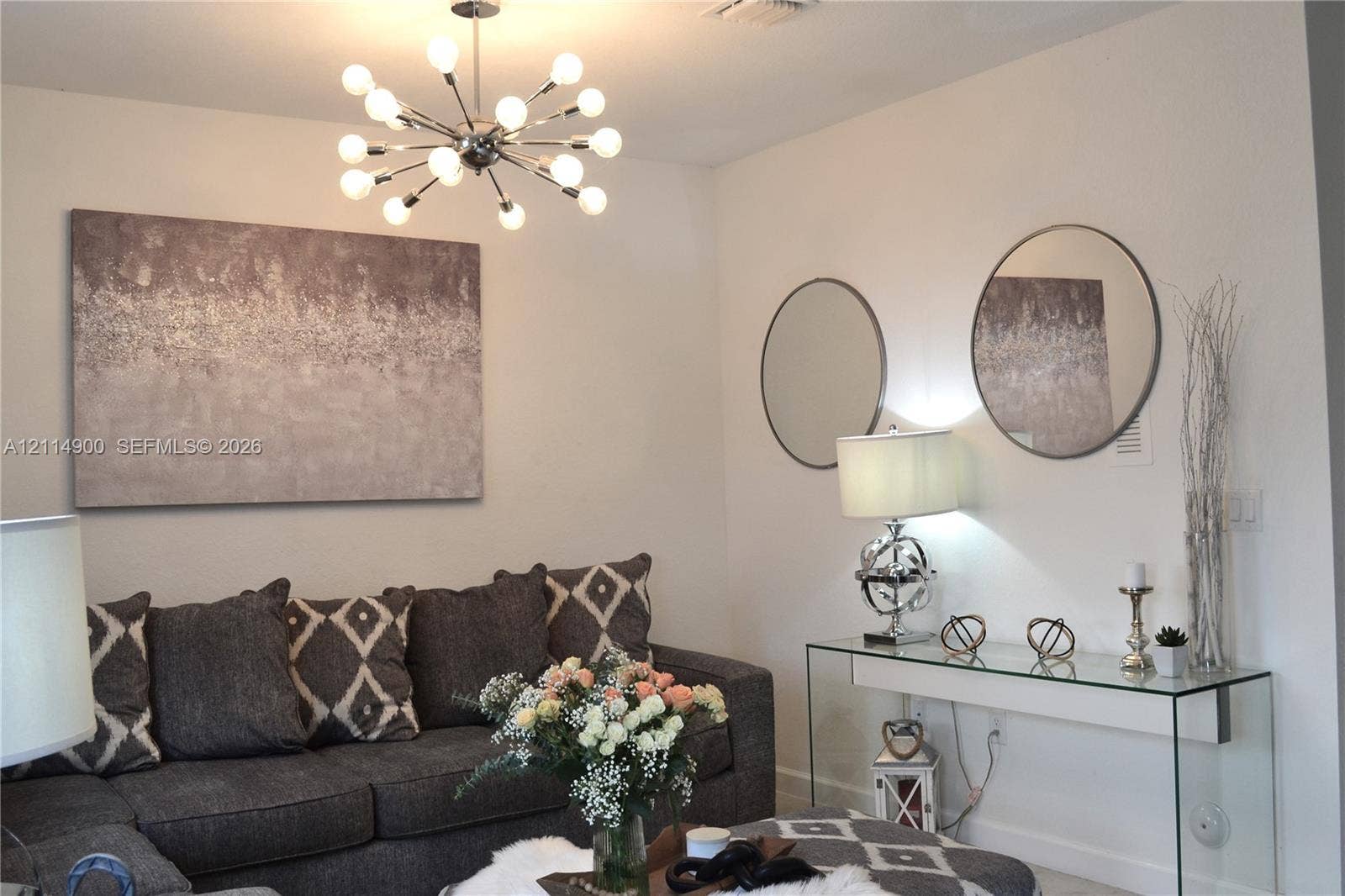 25048 SW 113th Place, Homestead, FL 33032 Sputnik-style multi-bulb chandelier with a polished chrome finish, two circular wall-mounted mirrors with metallic frames, and neutral interior wall paint
