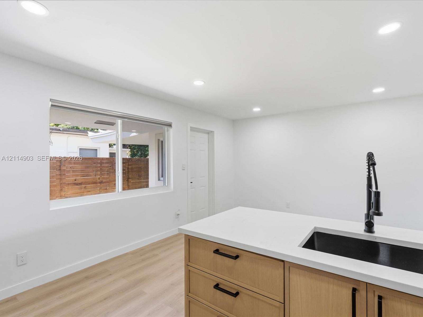 1129 NE 16th Avenue, #1, Fort Lauderdale, Fort Lauderdale, FL 33304 Kitchen island featuring wood-finish cabinetry, a white countertop, an undermount sink with a matte black pull-down faucet, recessed lighting, and wood-finish flooring