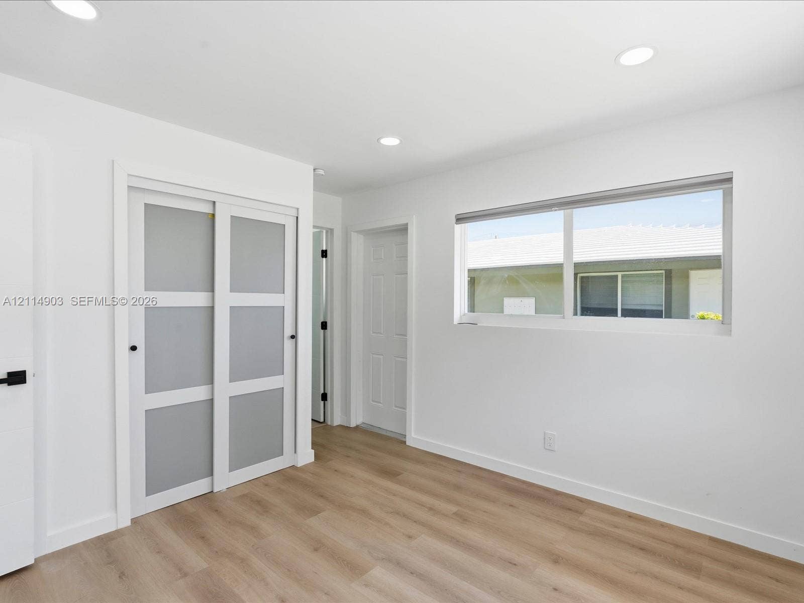 1129 NE 16th Avenue, #1, Fort Lauderdale, Fort Lauderdale, FL 33304 Interior room featuring wood-finish flooring, recessed lighting, sliding closet doors with frosted panels, and a multi-pane horizontal window