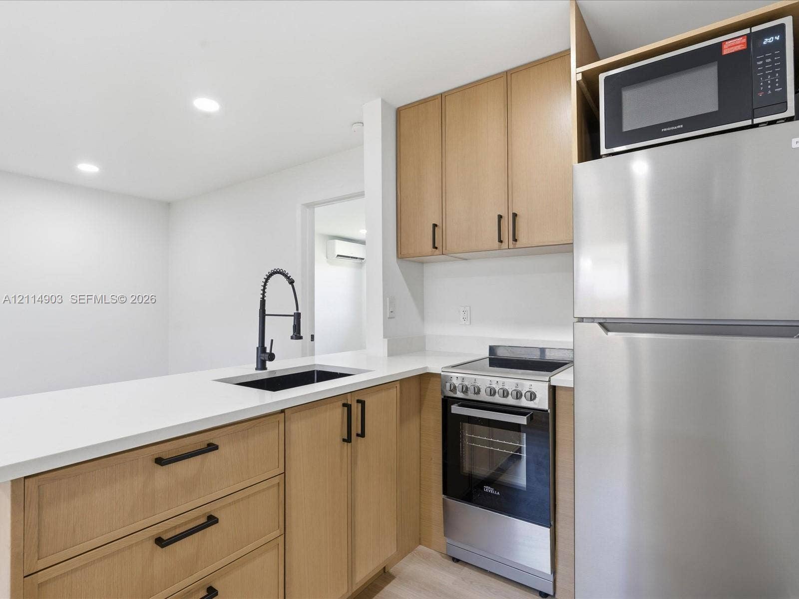 1129 NE 16th Avenue, #1, Fort Lauderdale, Fort Lauderdale, FL 33304 Kitchen featuring light wood-finish cabinetry, white countertops, a stainless steel refrigerator, a built-in microwave, and a matte black pulldown faucet