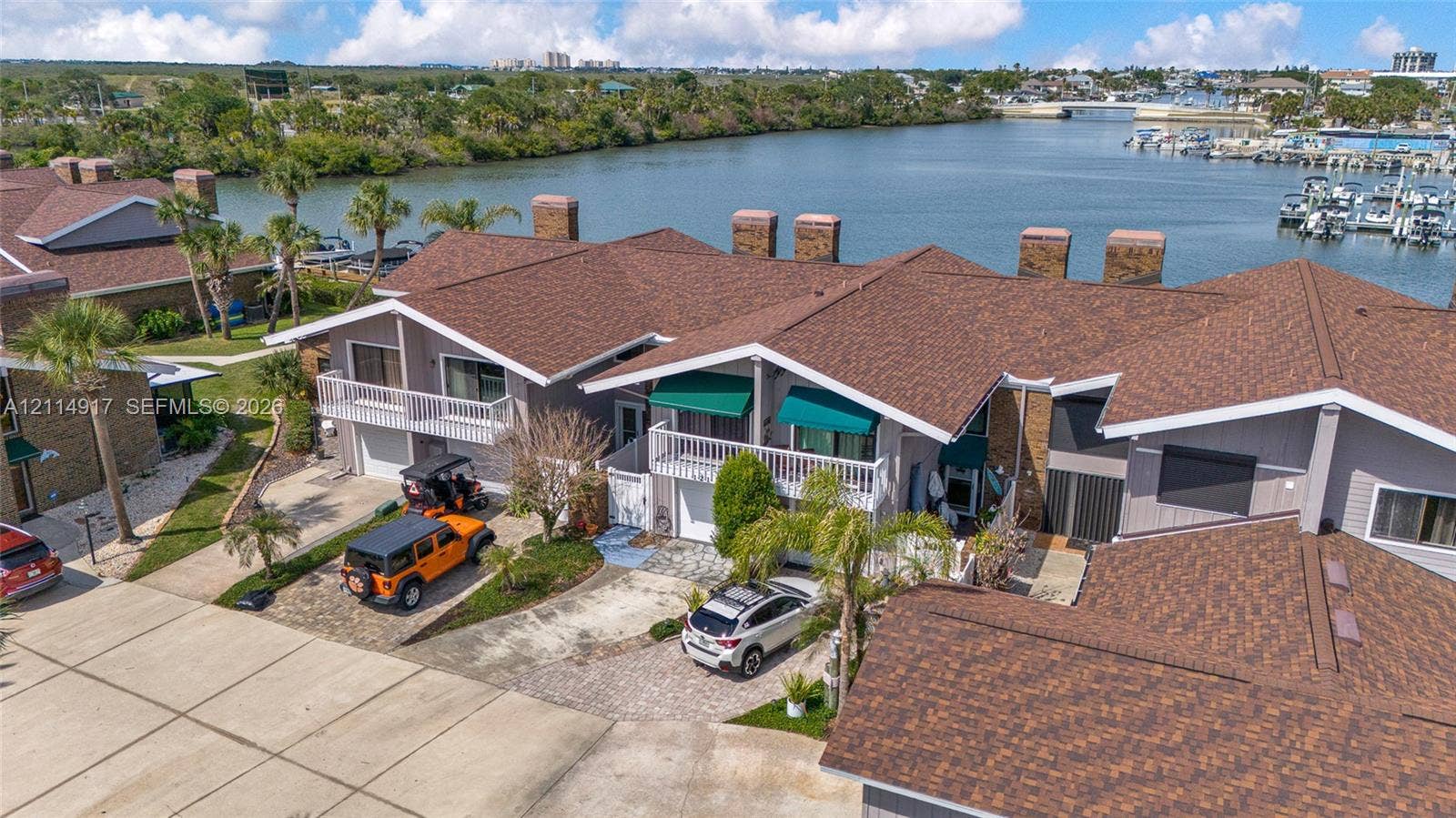 121 Lagoon, New Smyrna Beach, FL 32169 Waterfront townhome featuring a multi-gabled shingle roof, integrated garage, private balcony, and brick chimneys