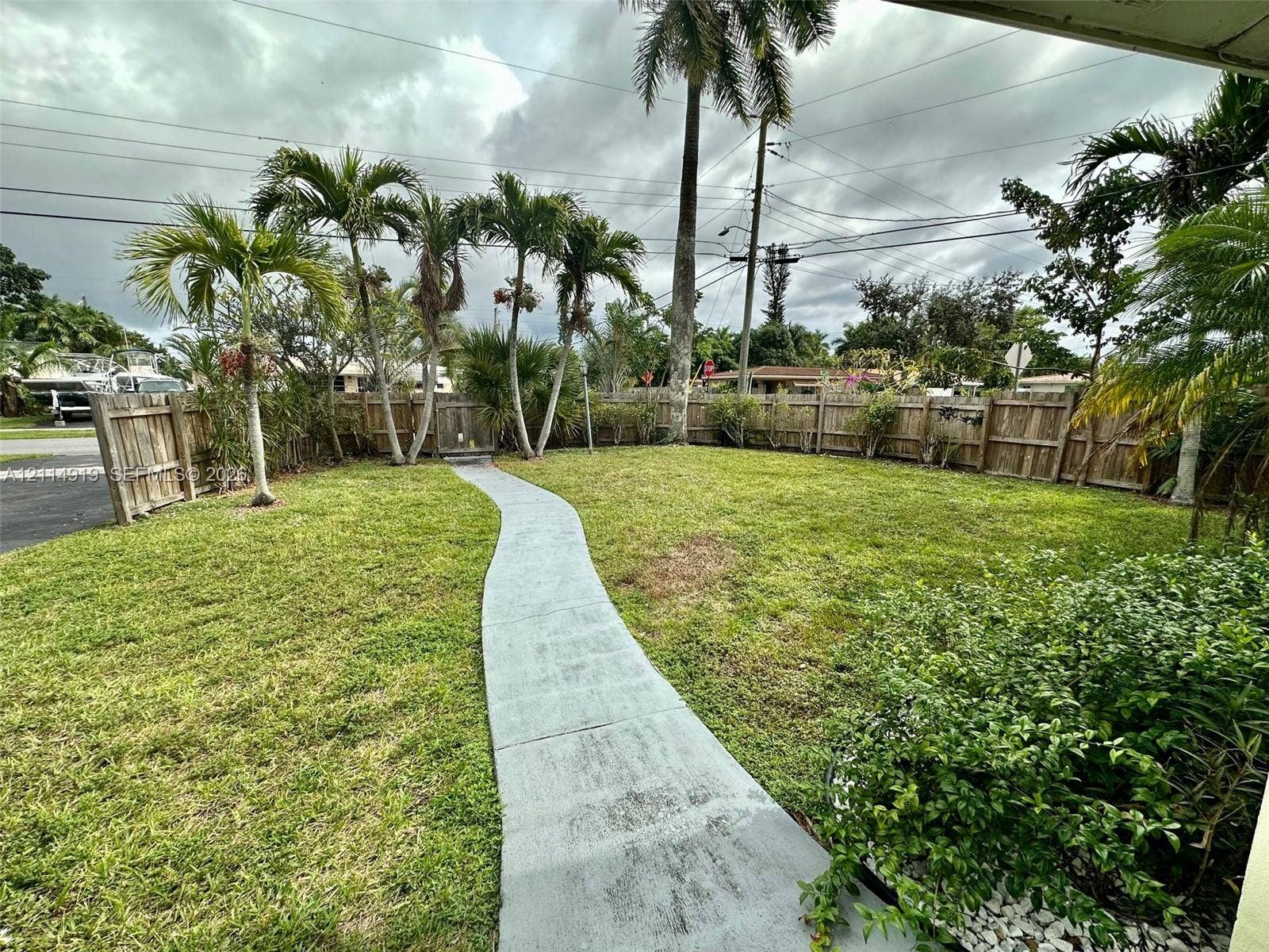 2901 NW 9th Terrace, #., Wilton Manors, Wilton Manors, FL 33311 Expansive yard featuring mature palm trees, a concrete walkway, and wood perimeter fencing