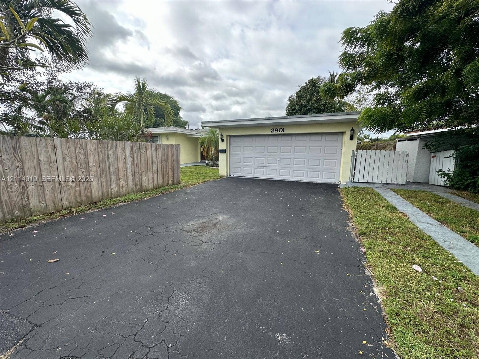 2901 NW 9th Terrace, #., Wilton Manors, Wilton Manors, FL 33311 Single-story exterior featuring a two-car garage, asphalt driveway, and wood-panel perimeter fencing