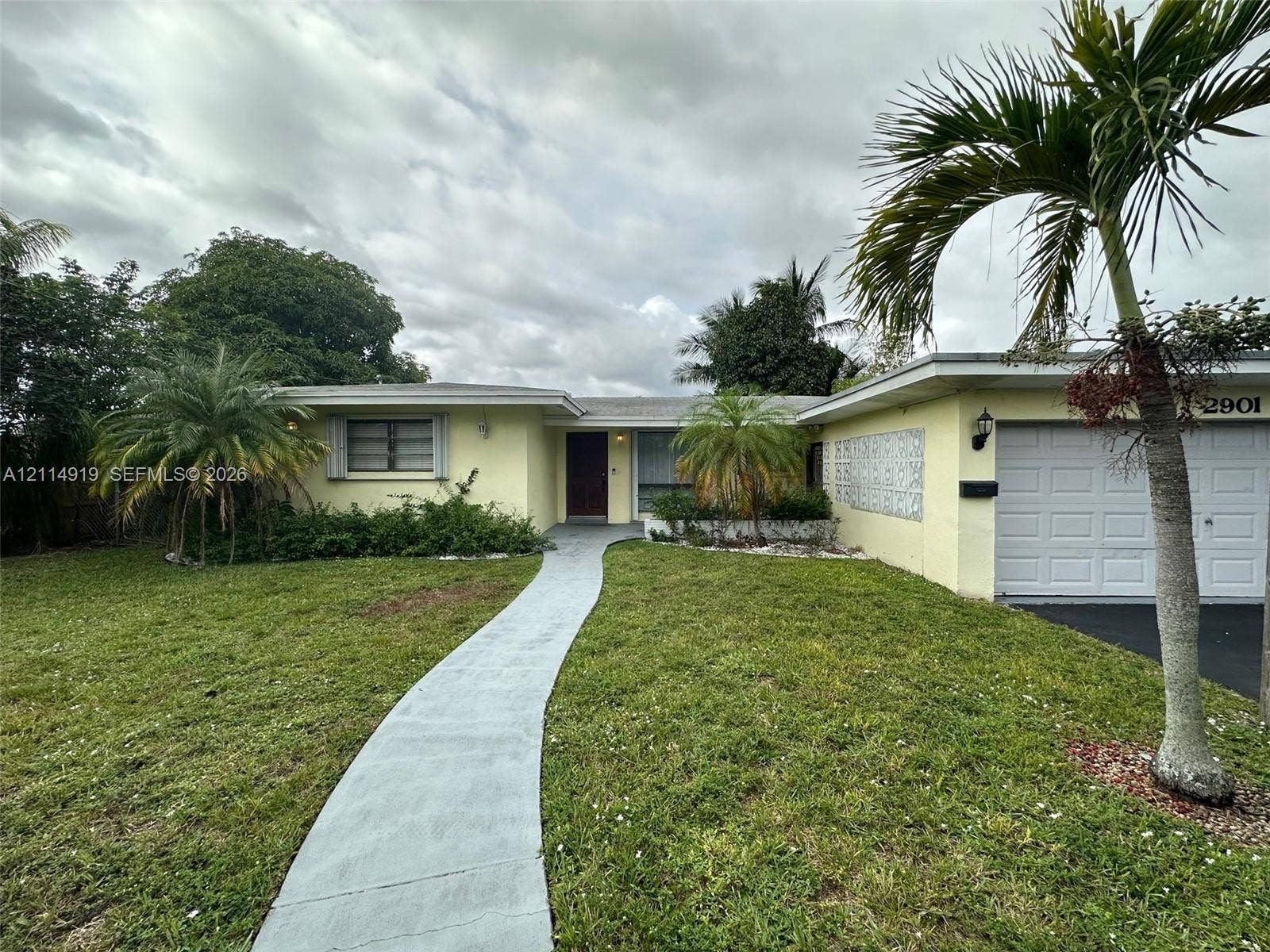 2901 NW 9th Terrace, #., Wilton Manors, Wilton Manors, FL 33311 Single-story residence featuring a painted stucco exterior, decorative breeze block wall detailing, an attached garage, and a concrete walkway