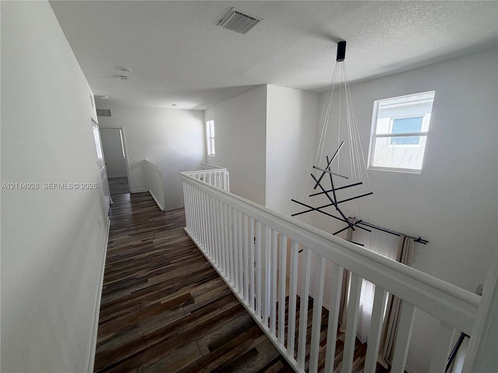 1411 SE 26th Road, Homestead, FL 33035 Wood-finish flooring, white spindle railing, and modern multi-arm chandelier