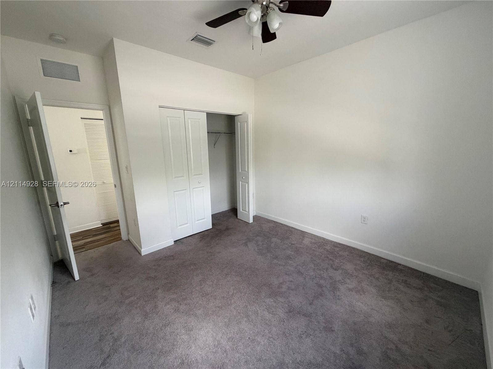 1411 SE 26th Road, Homestead, FL 33035 Neutral carpeted flooring, closet with bi-fold doors, and a ceiling-mounted light fixture with a fan