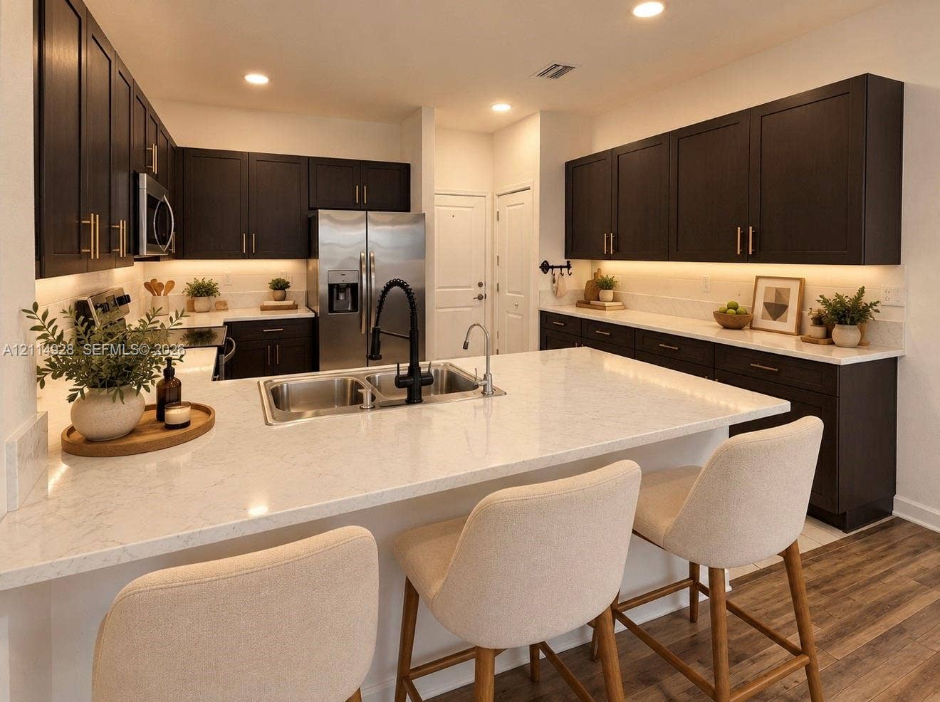 1411 SE 26th Road, Homestead, FL 33035 Kitchen featuring dark cabinetry, expansive quartz countertops, an undermount double-basin sink with a matte black faucet, integrated under-cabinet lighting, and wood-finish flooring