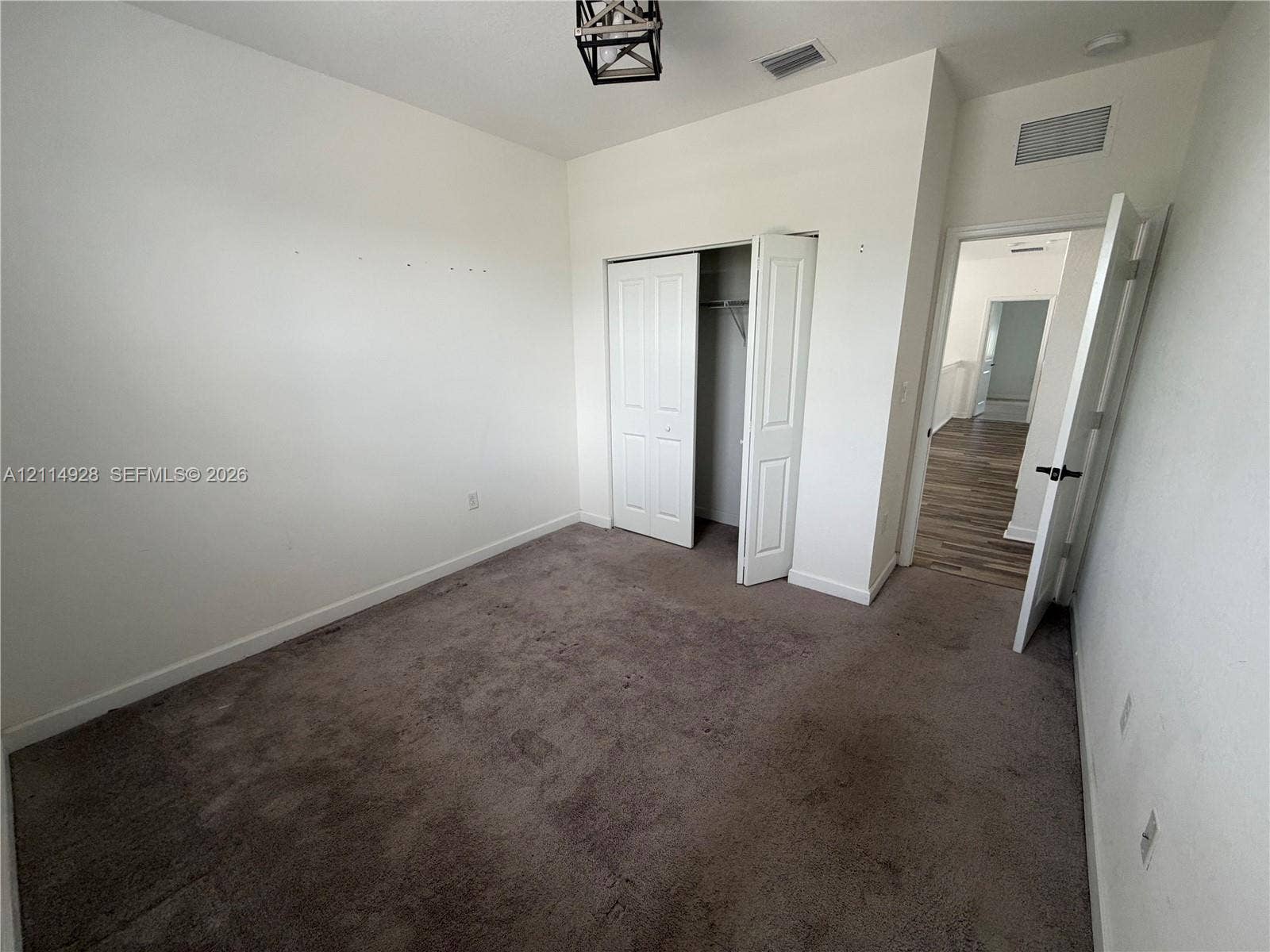 1411 SE 26th Road, Homestead, FL 33035 Room featuring neutral wall tones, plush carpeting, a closet with double-panel doors, and an overhead geometric metal light fixture