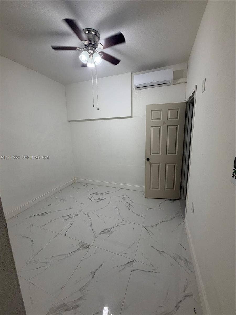 1411 SE 26th Road, Homestead, FL 33035 Large-format tile flooring featuring a marble-style pattern, ceiling fan with integrated lighting, and wall-mounted ductless climate control unit