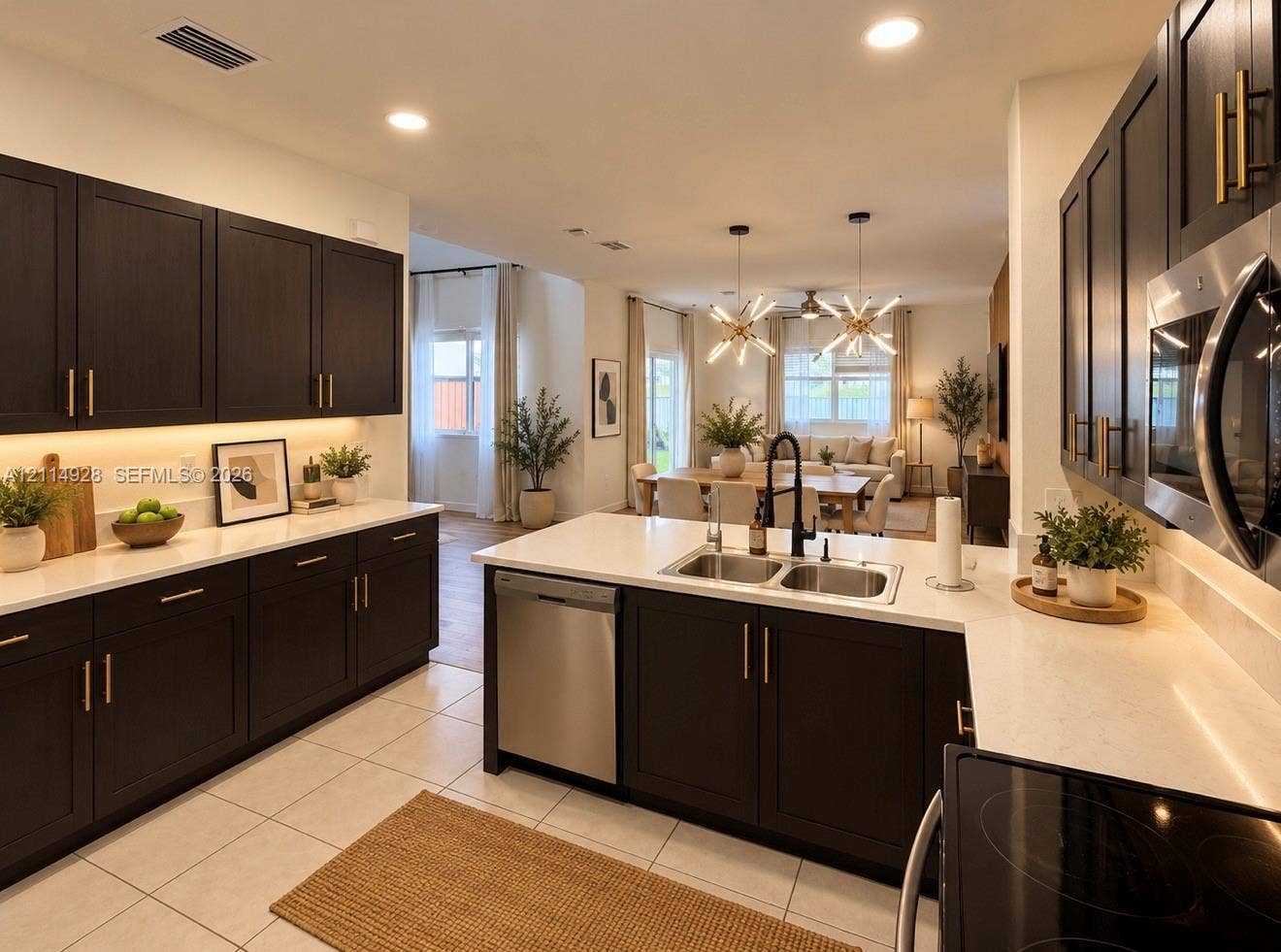 1411 SE 26th Road, Homestead, FL 33035 Kitchen featuring dark wood-finish cabinetry with gold-tone hardware, white stone-composite countertops, under-cabinet lighting, a stainless steel undermount sink with a matte black faucet, and recessed ceiling lighting