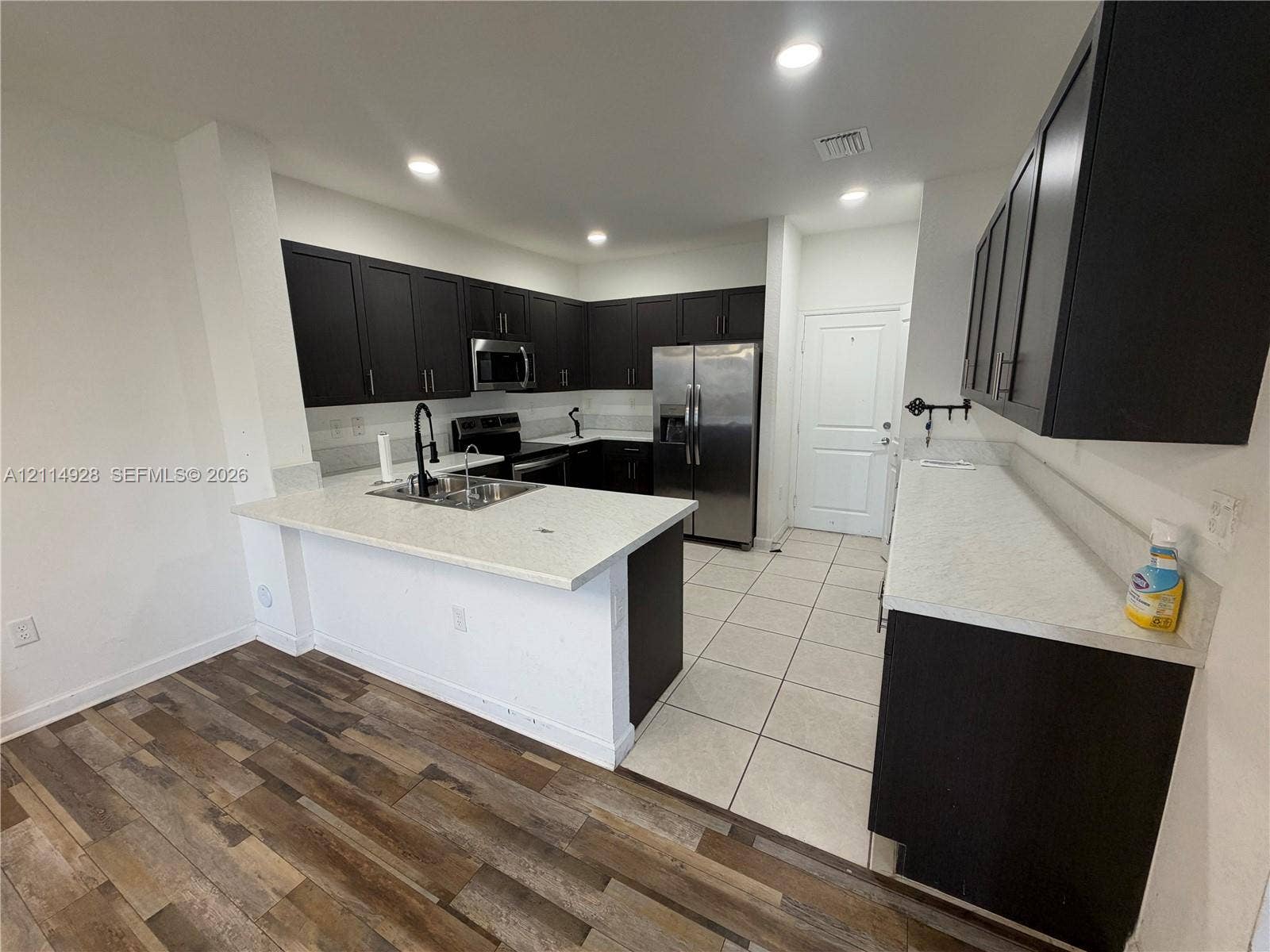 1411 SE 26th Road, Homestead, FL 33035 Kitchen featuring dark cabinetry, stone-finish countertops, stainless steel appliances, recessed lighting, and a combination of wood-finish and tile flooring