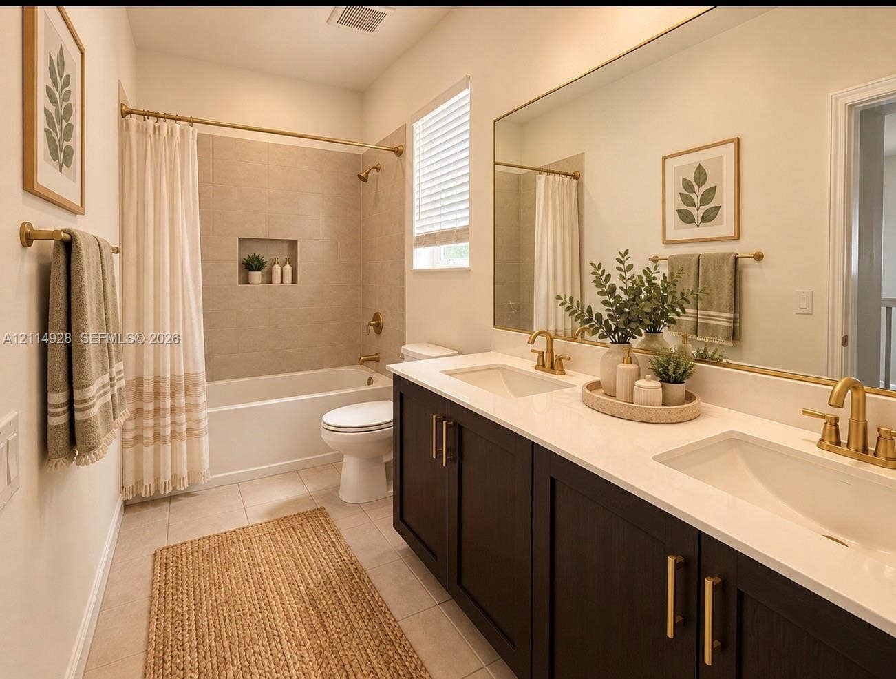 1411 SE 26th Road, Homestead, FL 33035 Bathroom featuring a dual-sink vanity with a solid-surface countertop, dark-finish cabinetry, brushed-gold hardware, and a tiled shower surround with an inset niche