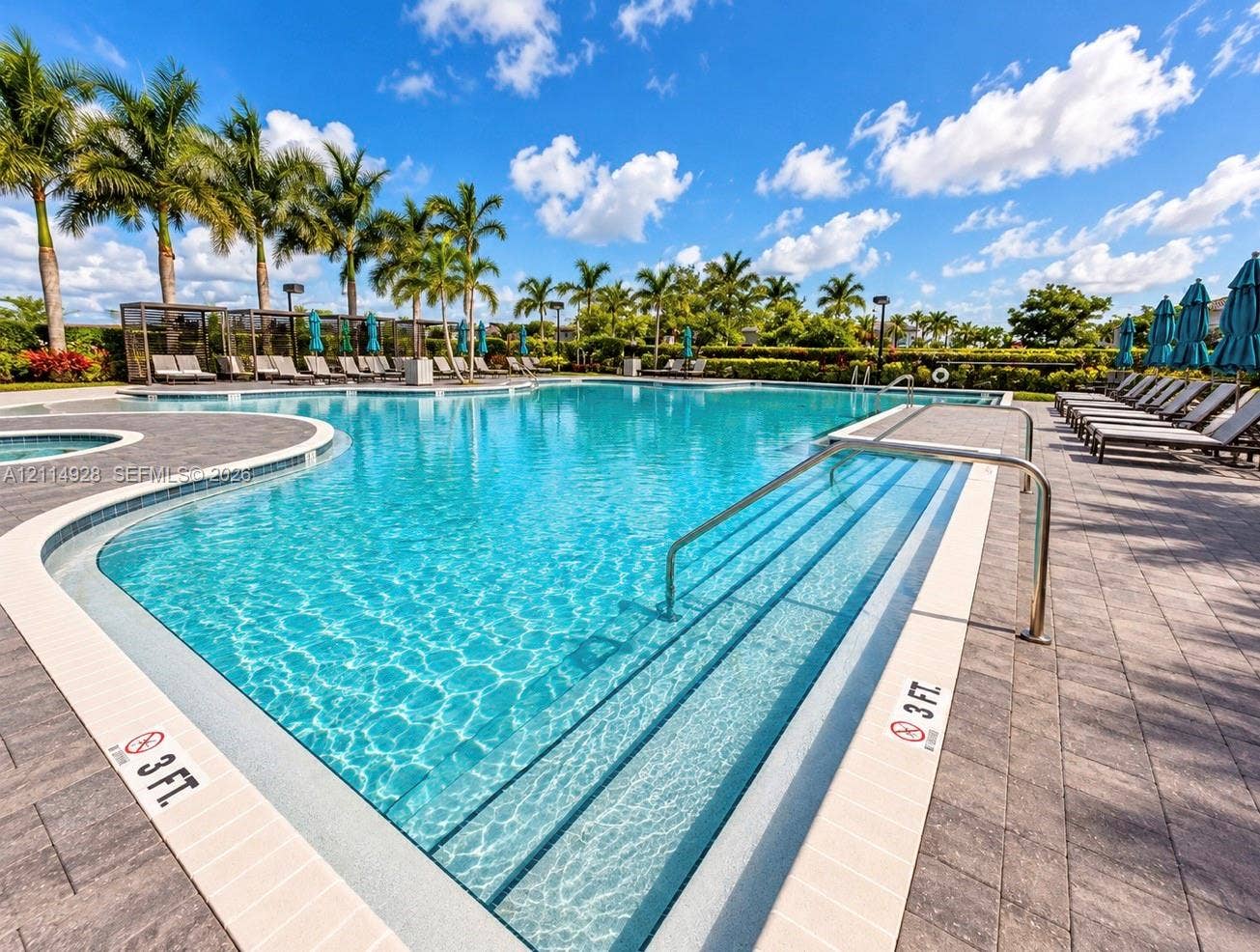 1411 SE 26th Road, Homestead, FL 33035 Resort-style swimming pool featuring integrated steps, paver-stone decking, and mature palm tree landscaping