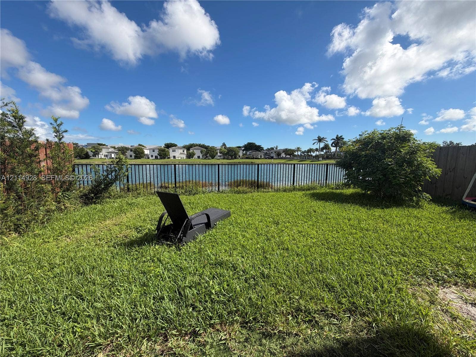 1411 SE 26th Road, Homestead, FL 33035 Backyard featuring a grass lawn, metal perimeter fencing, and water frontage