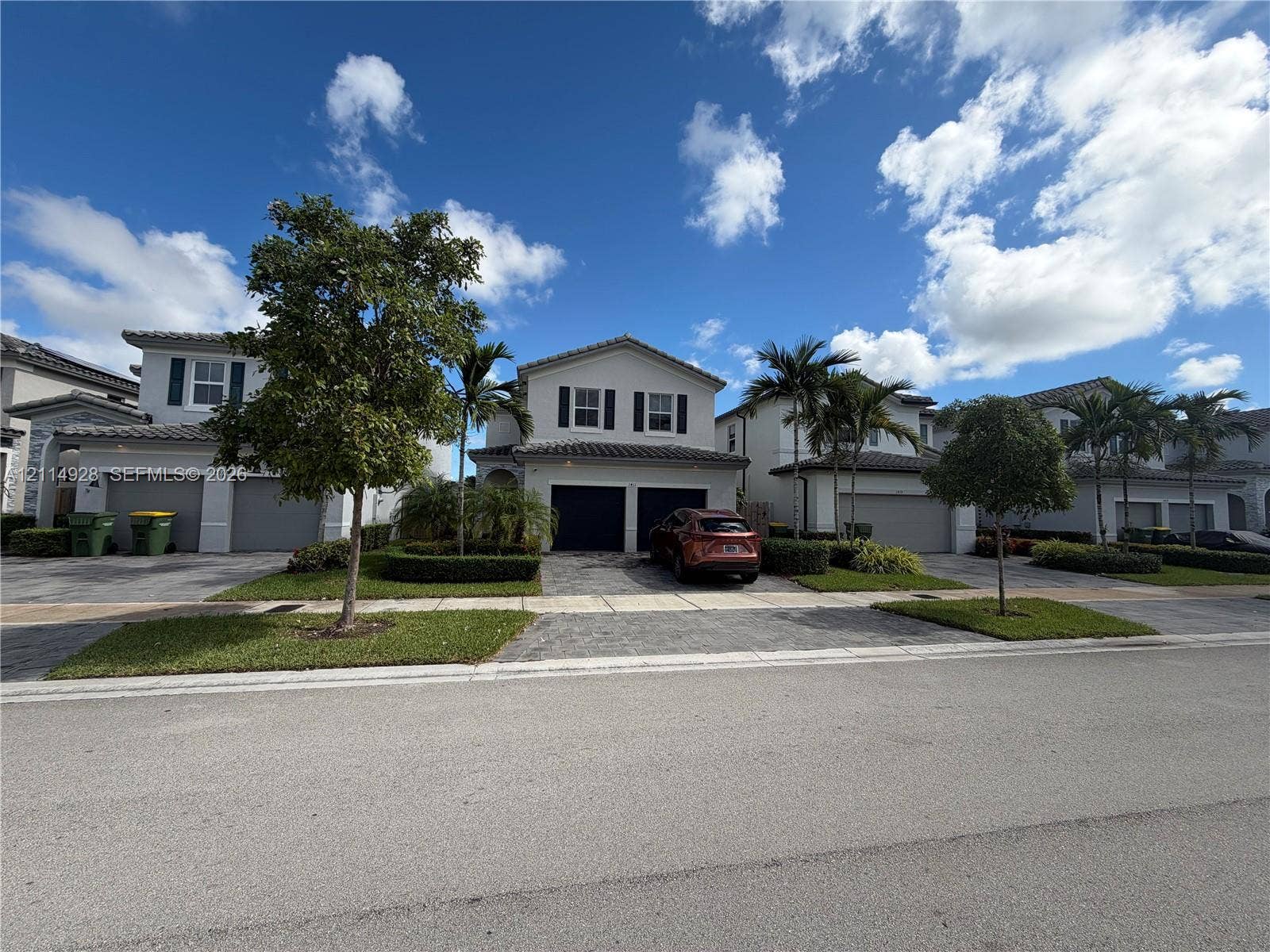 1411 SE 26th Road, Homestead, FL 33035 Two-story exterior featuring a tile roof, paved driveway, two-car garage, and manicured landscaping
